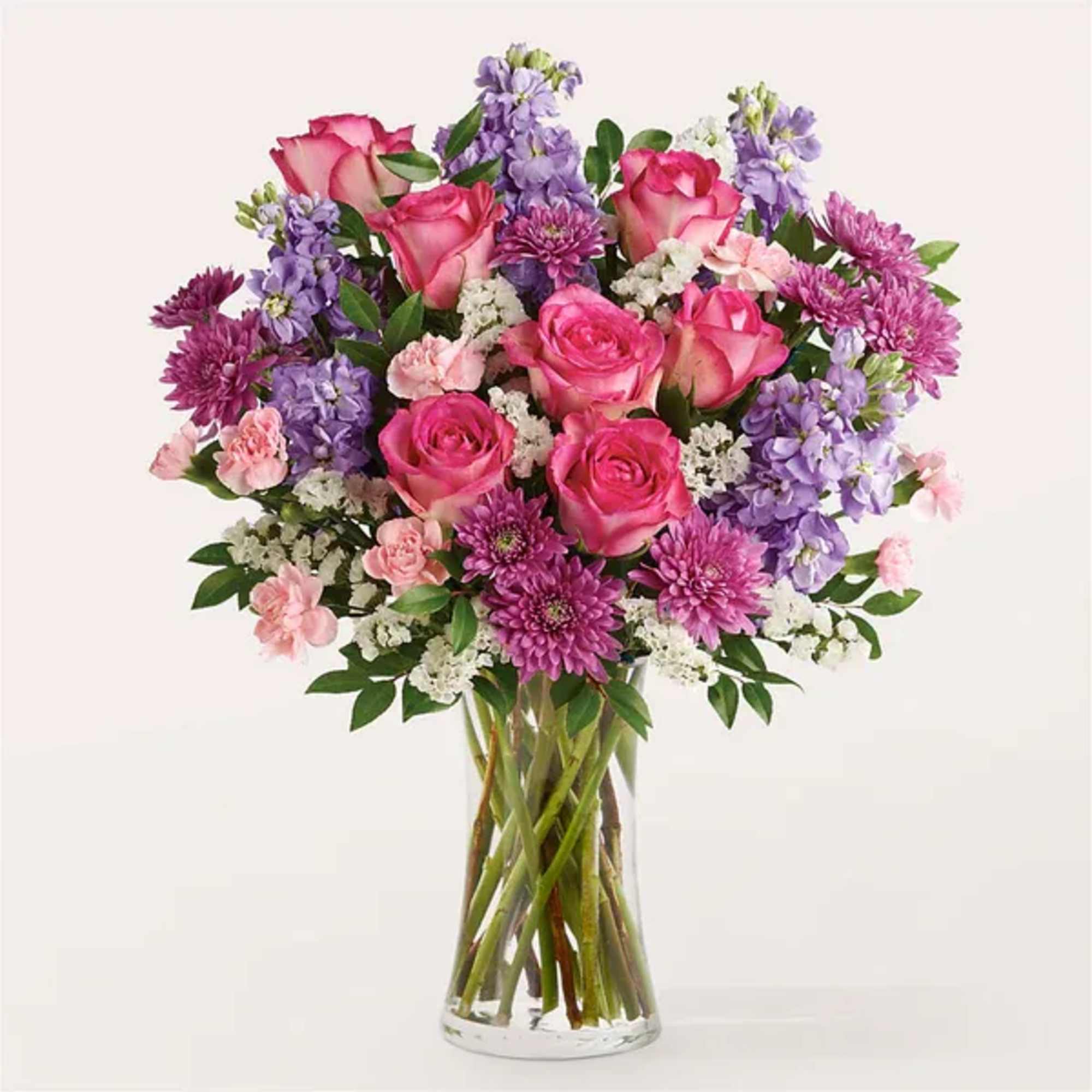 Pink roses and purple mixed flowers in a clear glass vase
