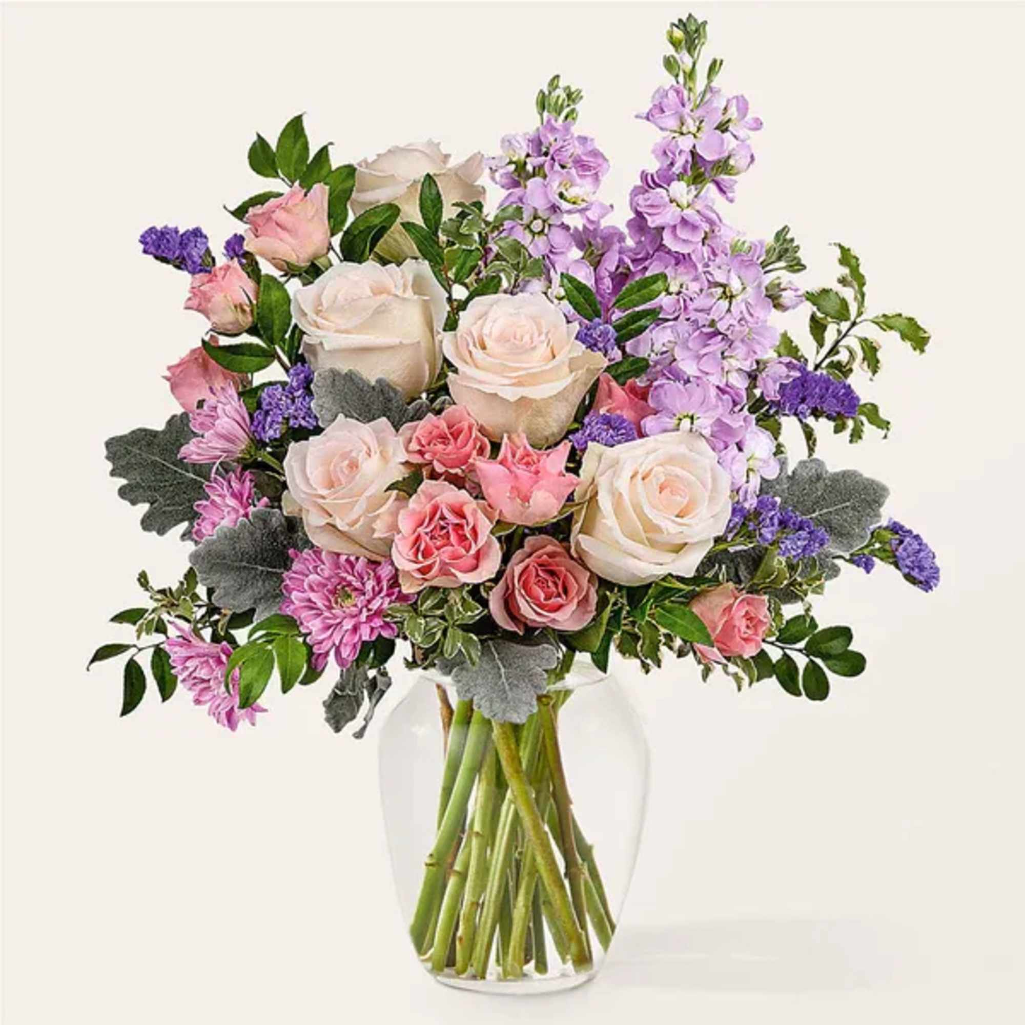Bouquet of pink and white roses with purple flowers in a clear glass vase