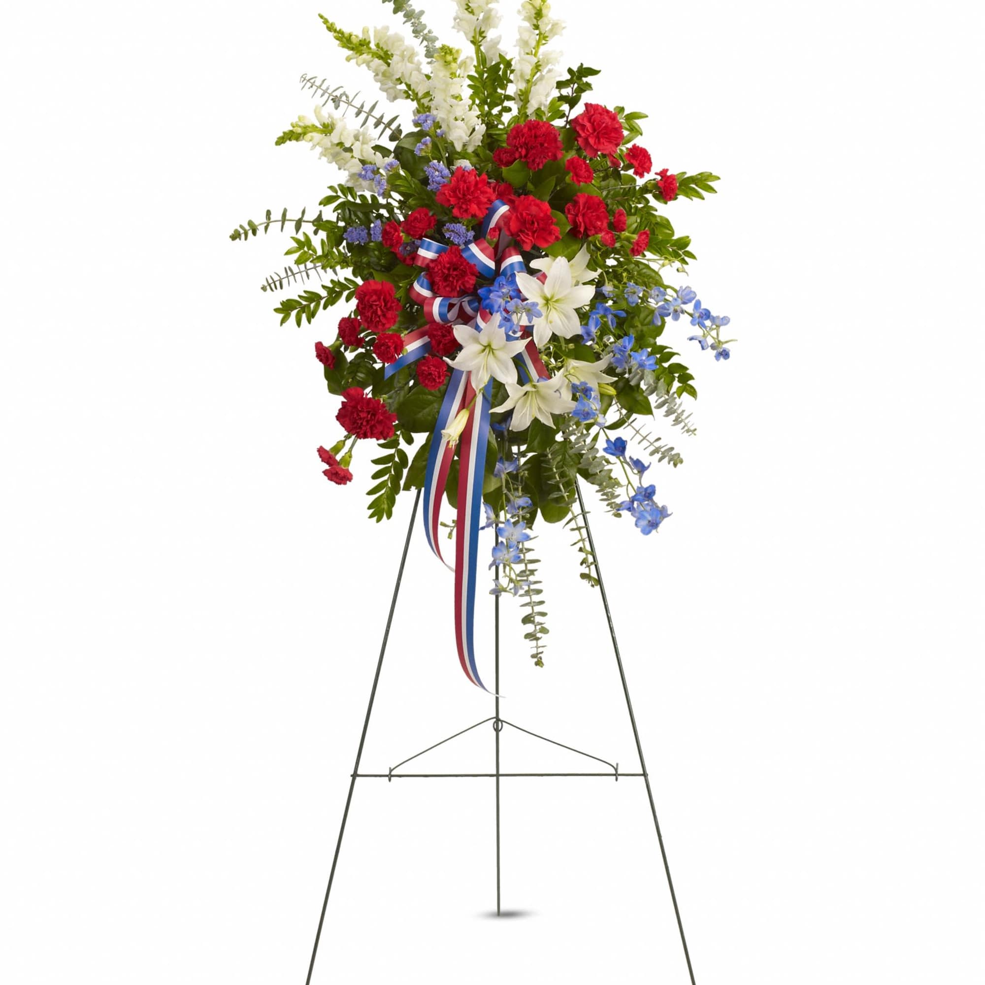 Tall red, white, and blue standing spray with carnations, lilies, and ribbon on a metal easel.
