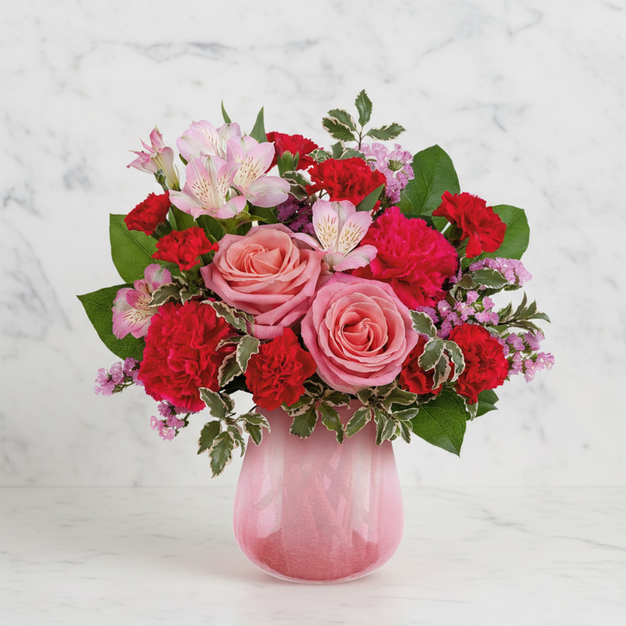 Pink roses and red carnations in a pink glass vase