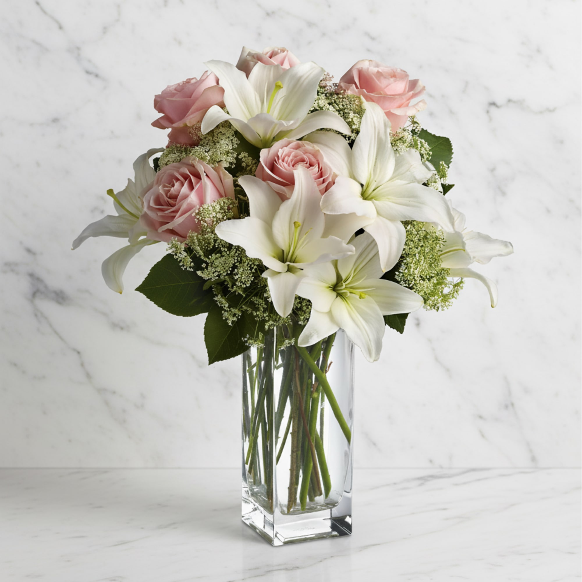 Pink roses and white lilies arranged in a clear glass vase