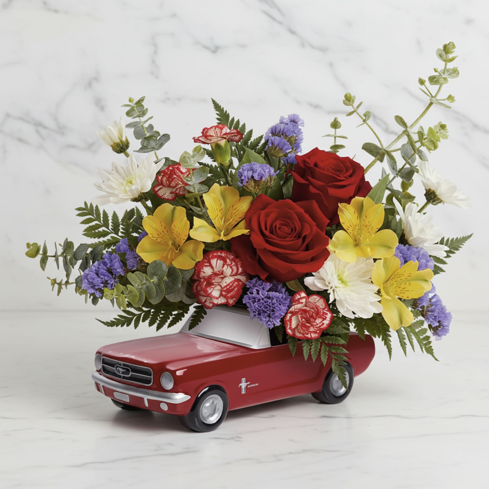 Red roses and mixed flowers arranged in a red toy car container