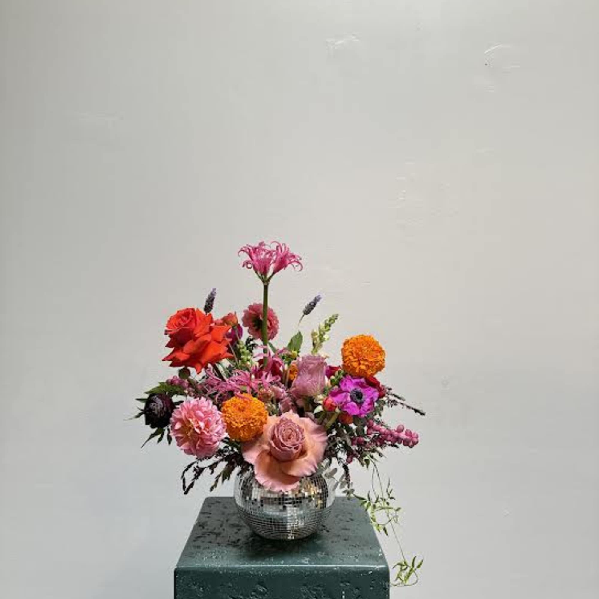 Colorful mixed flower arrangement in a mirrored vase on a pedestal