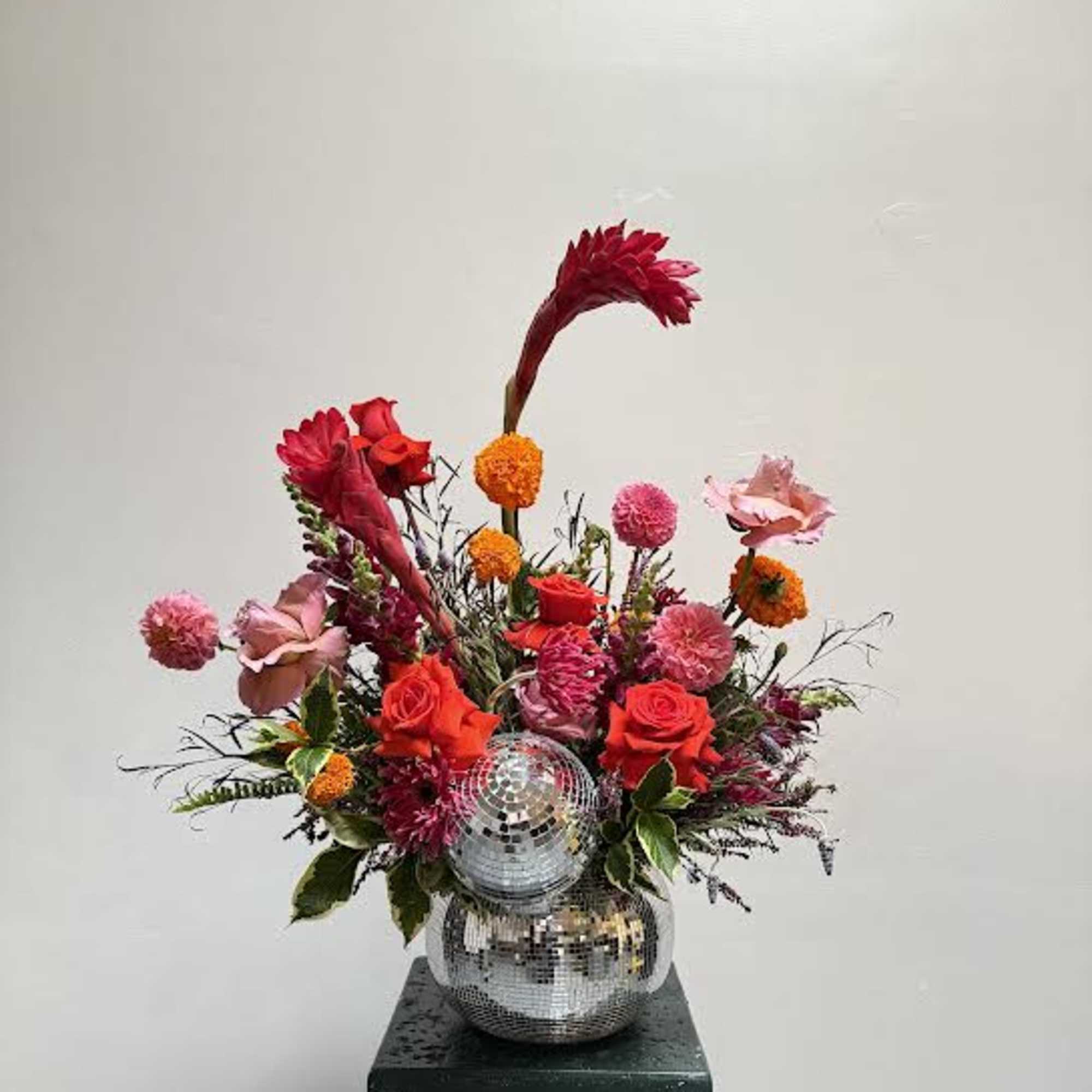 Bright mixed floral arrangement in a mirrored vase with a disco ball accent