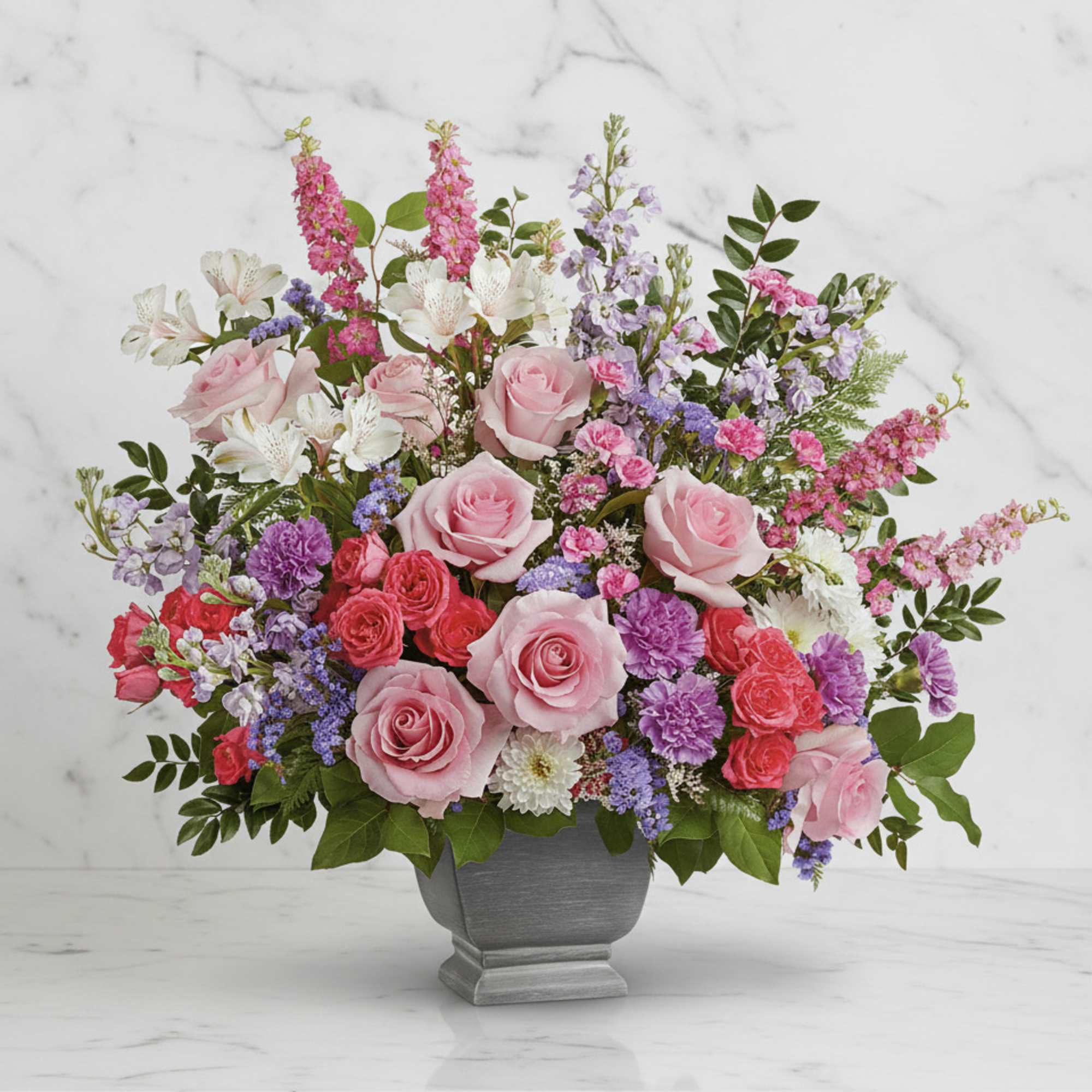Pink roses and mixed flowers arranged in a gray vase