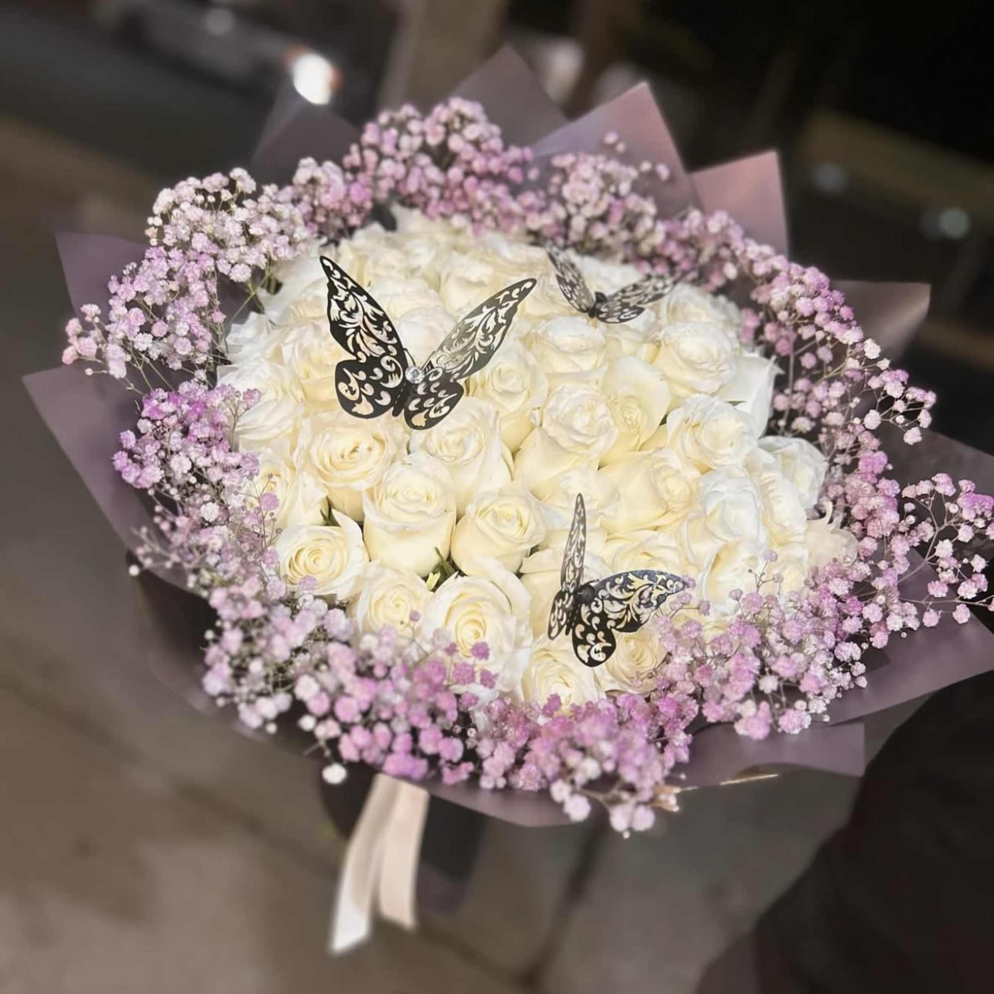 Bouquet of white roses with pink baby's breath and butterfly picks