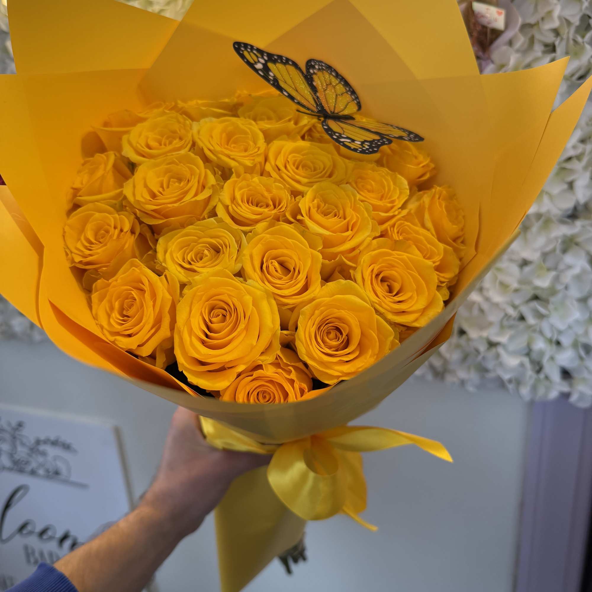 Bouquet of yellow roses wrapped in bright yellow paper with a butterfly decoration
