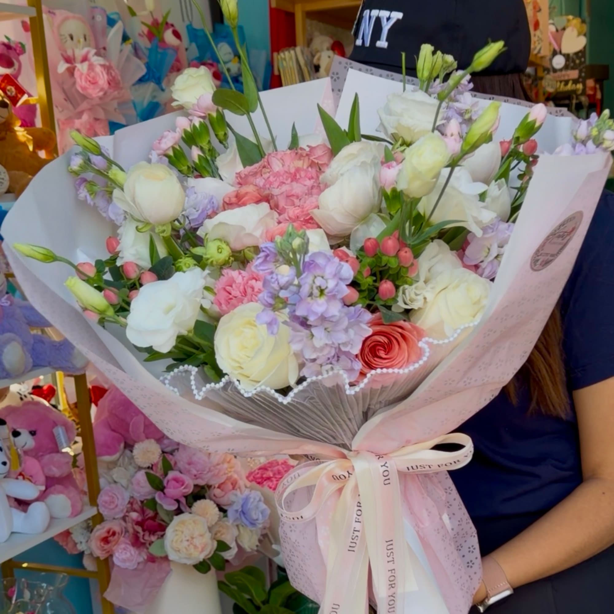 Large pastel bouquet of white, pink, and lavender flowers wrapped in pink paper