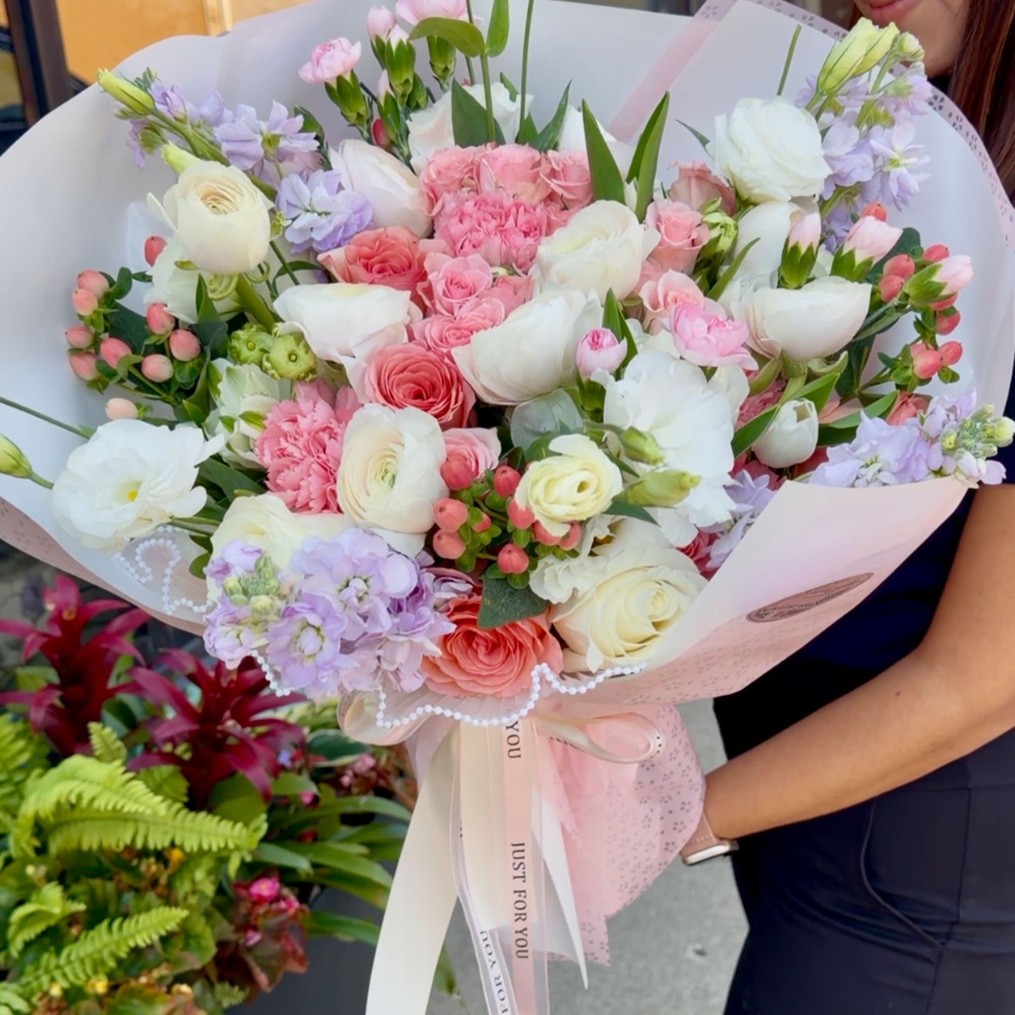 Large pastel bouquet of pink, white, and lavender flowers wrapped in pink paper