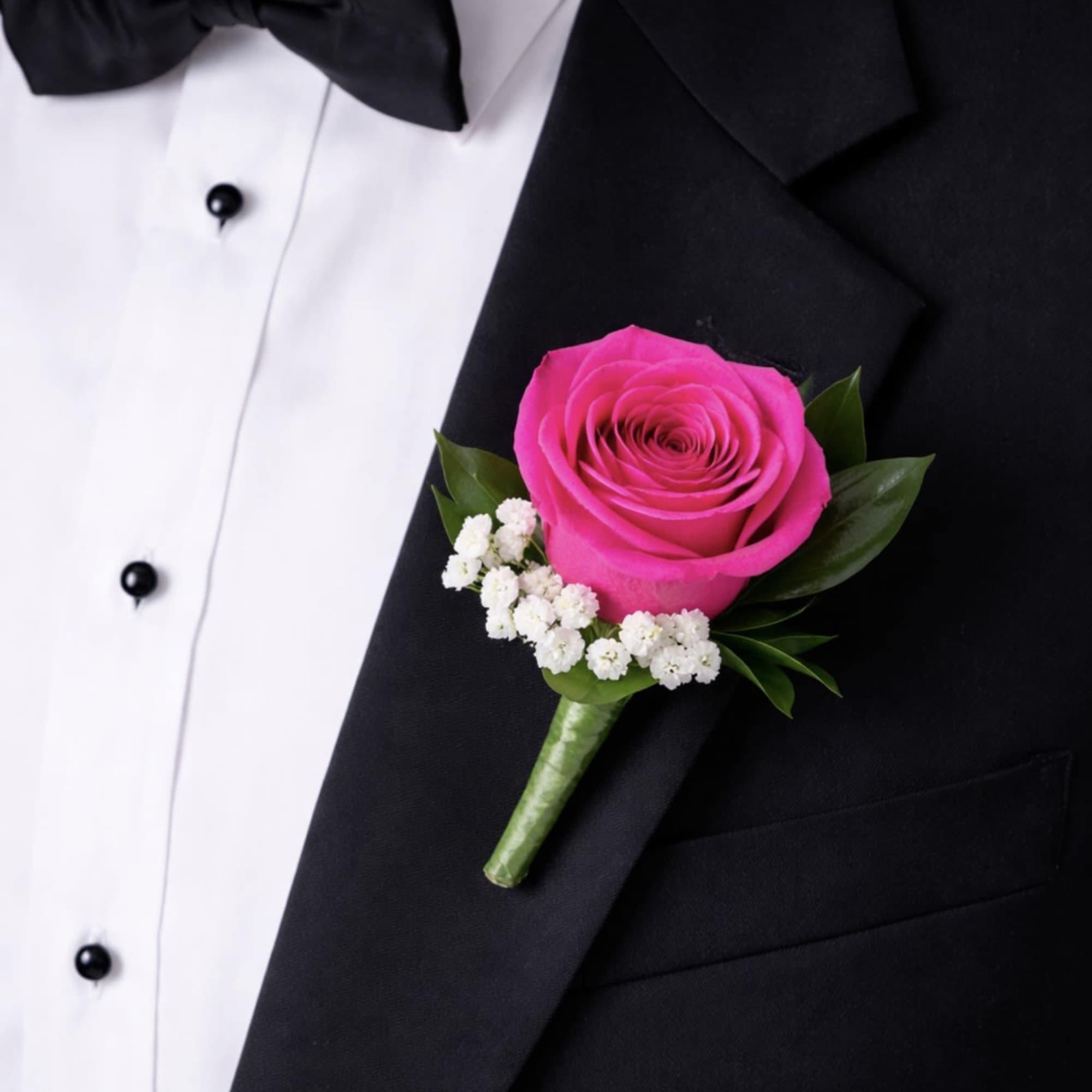 This hot pink rose boutonniere is a timeless lapel accessory featuring a