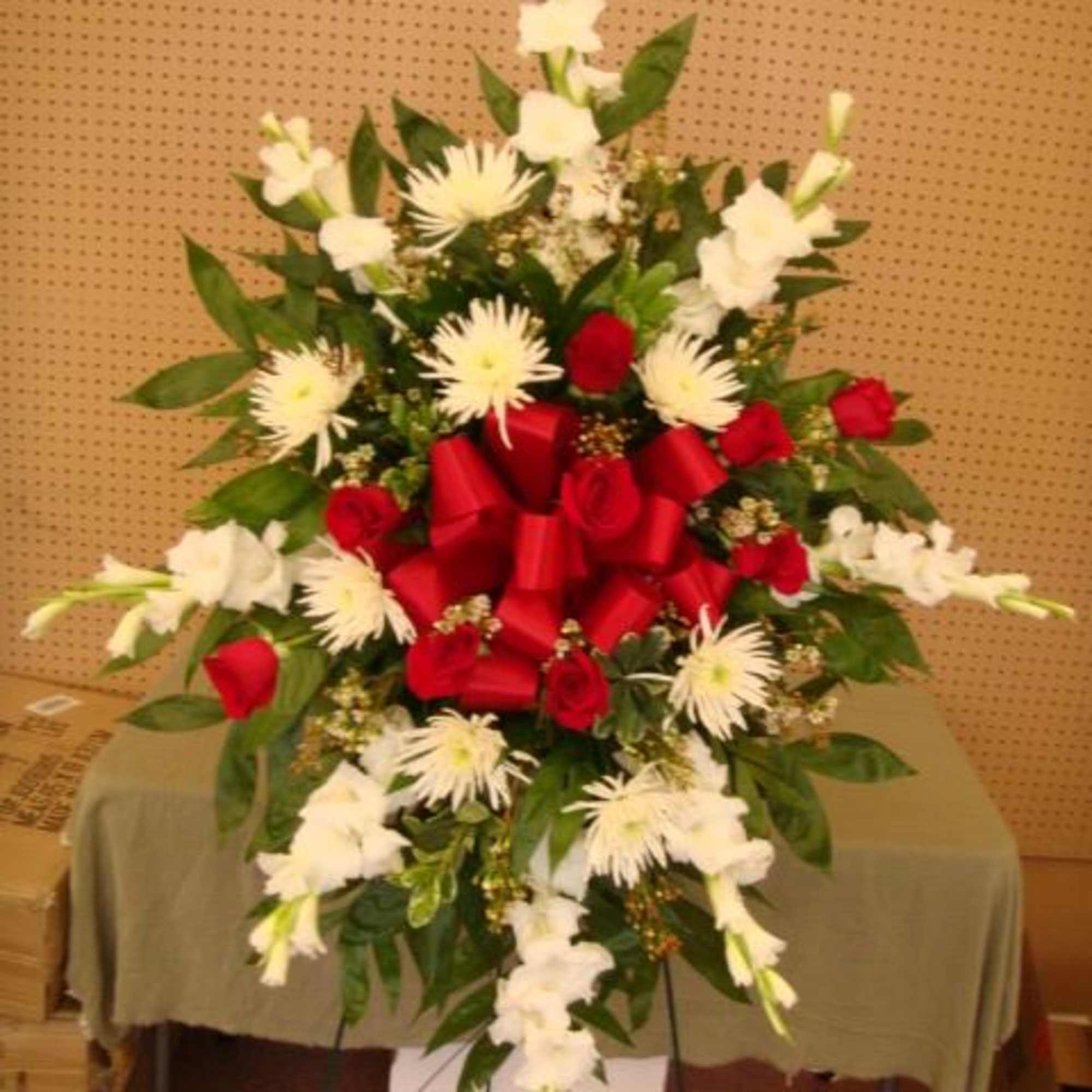 Large standing floral spray with red and white flowers and a red ribbon bow