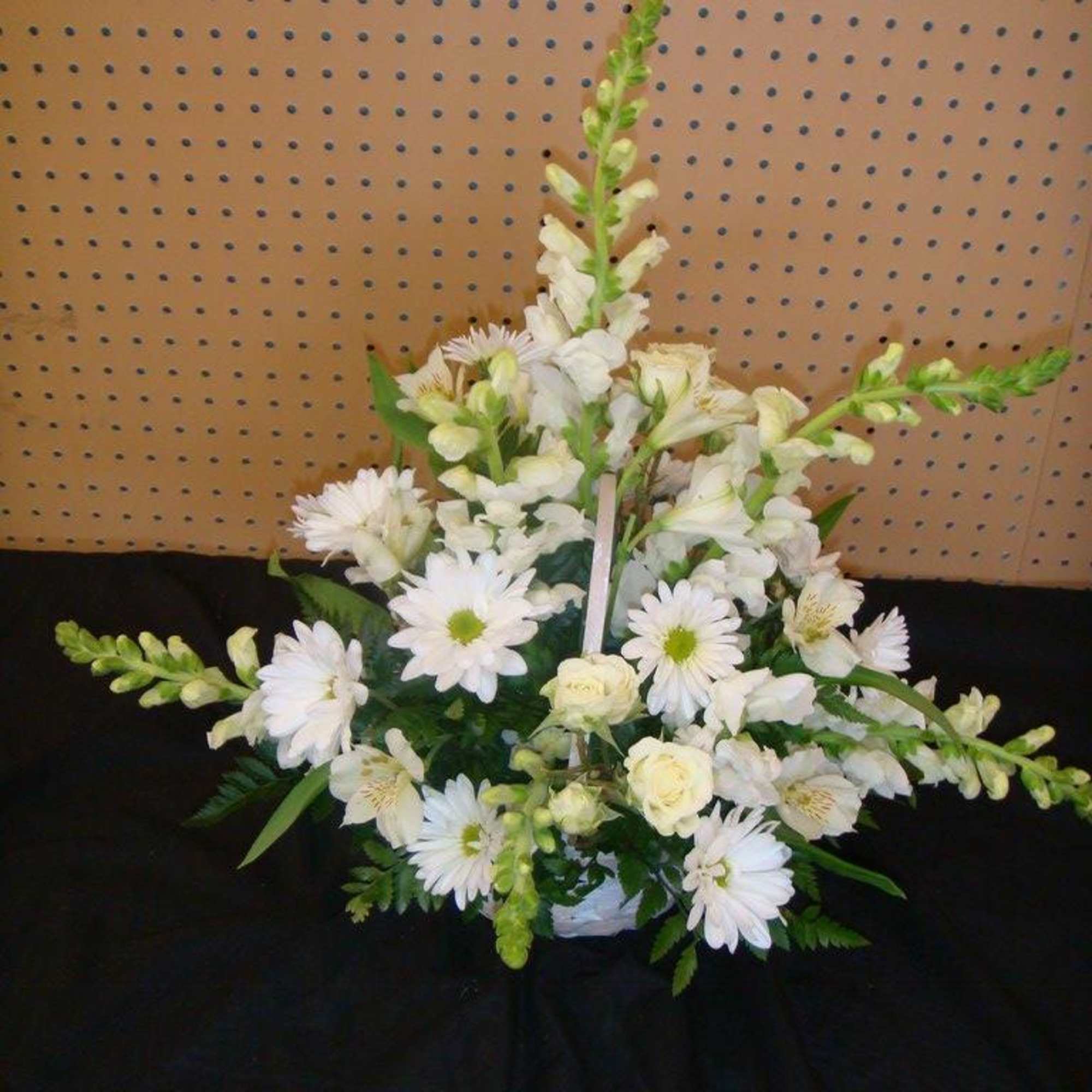 White floral arrangement with daisies and roses in a low container