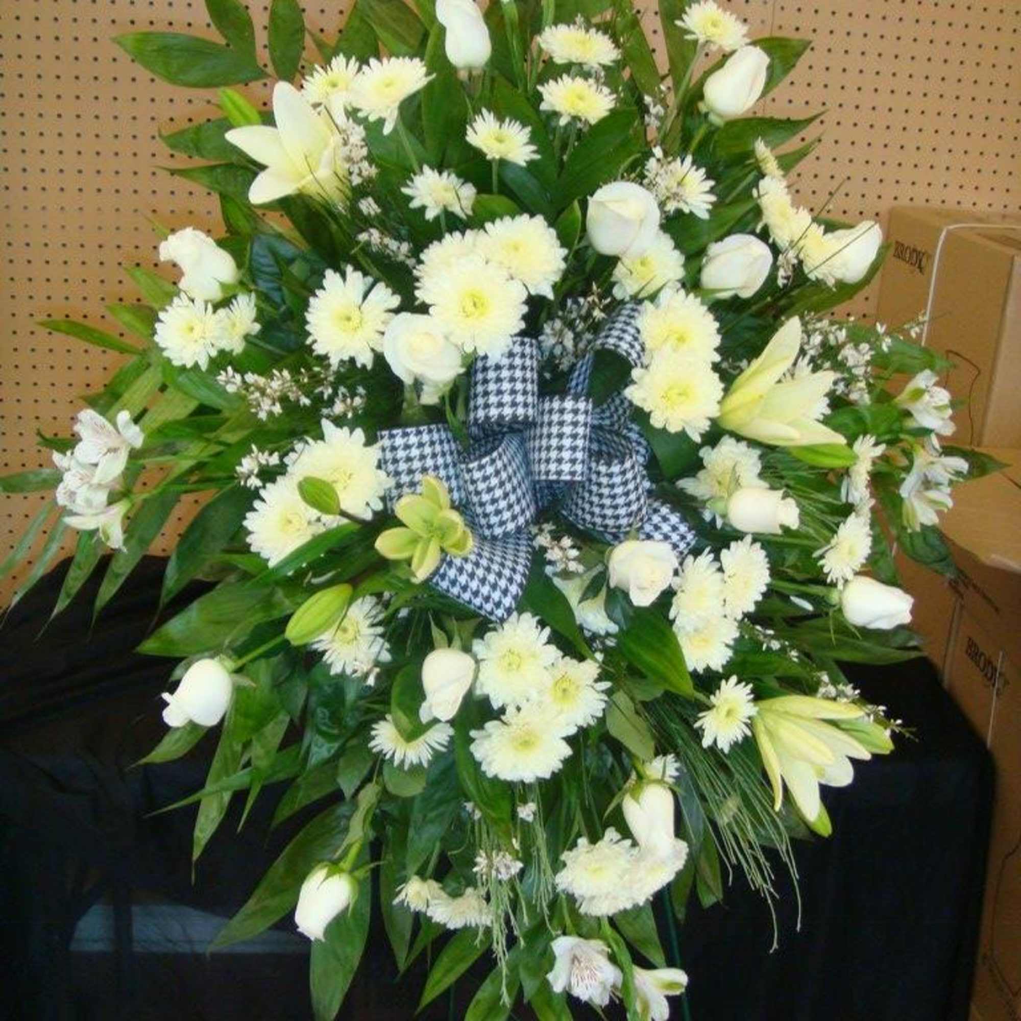 White floral standing spray with a checkered ribbon bow