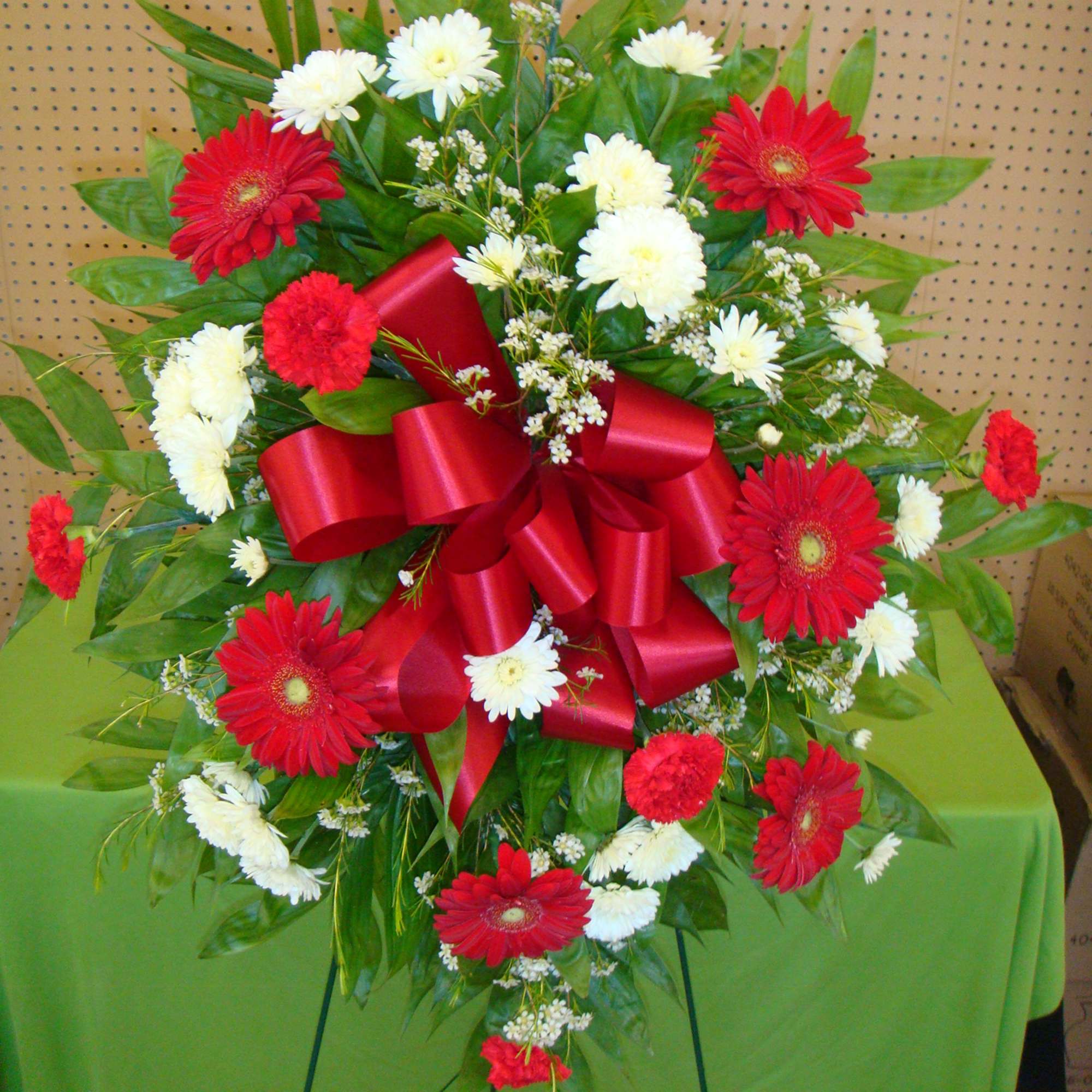 Standing floral spray with red and white flowers and a large red ribbon