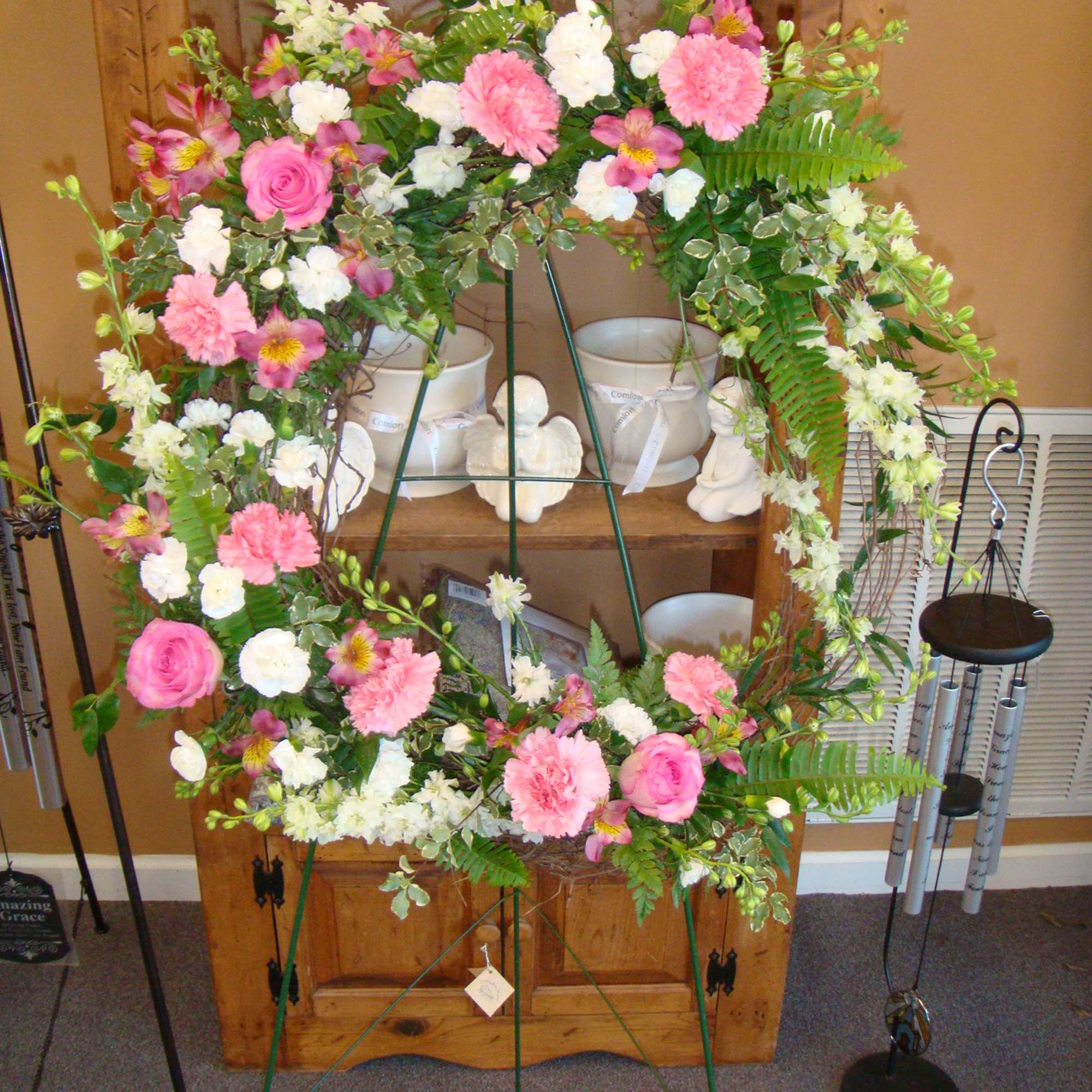 Heart-shaped floral wreath with pink and white flowers on a stand