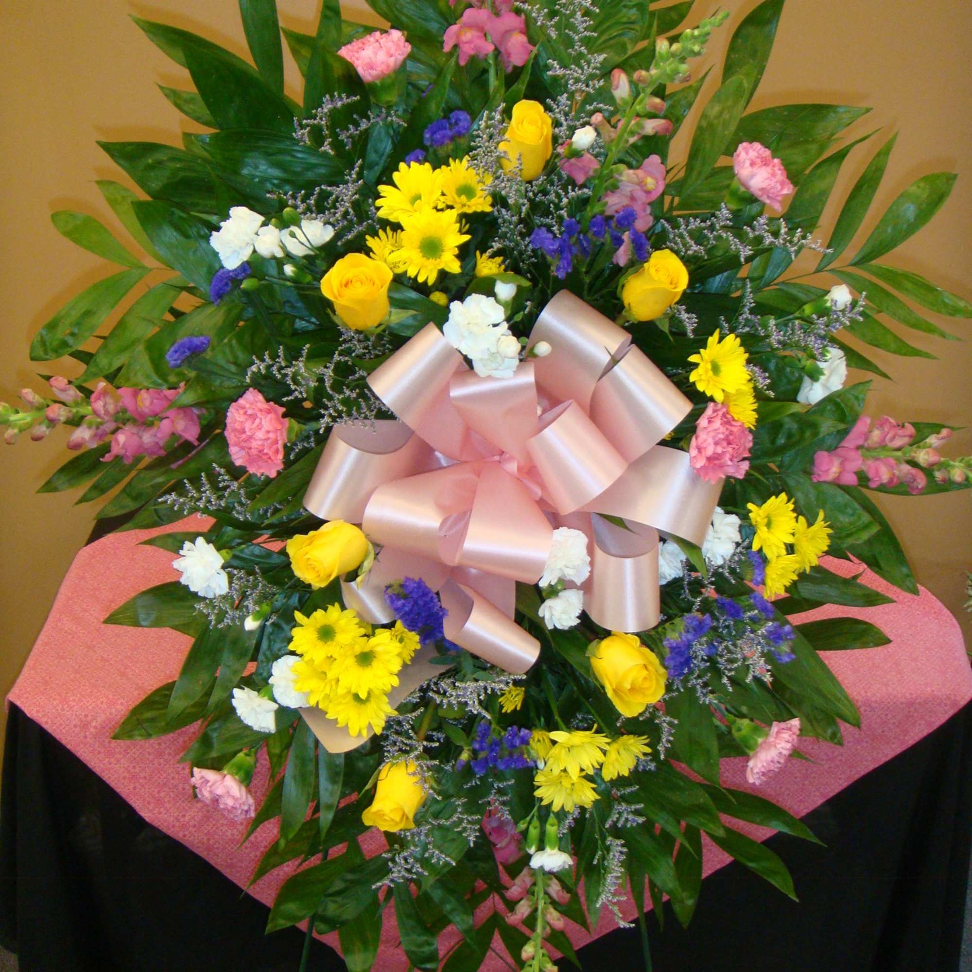 Large standing floral spray with pink ribbon and mixed blooms