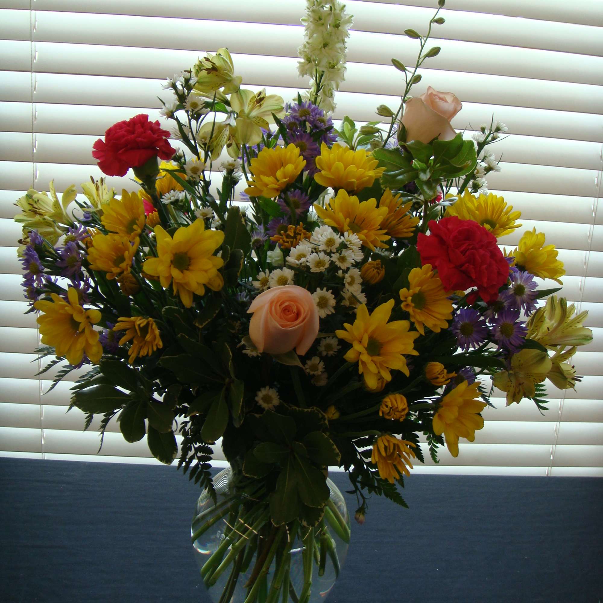 Mixed bouquet of yellow, red, pink, and purple flowers in a glass vase, photo 2 of 2