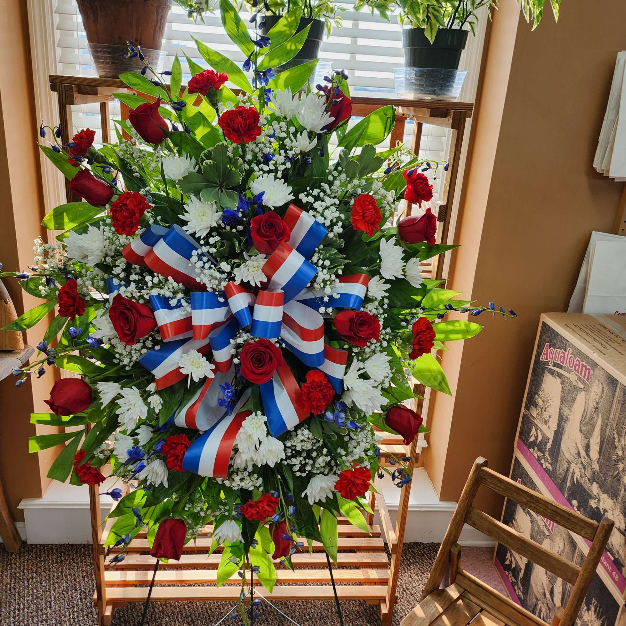 Large red, white, and blue floral standing spray with ribbon bow
