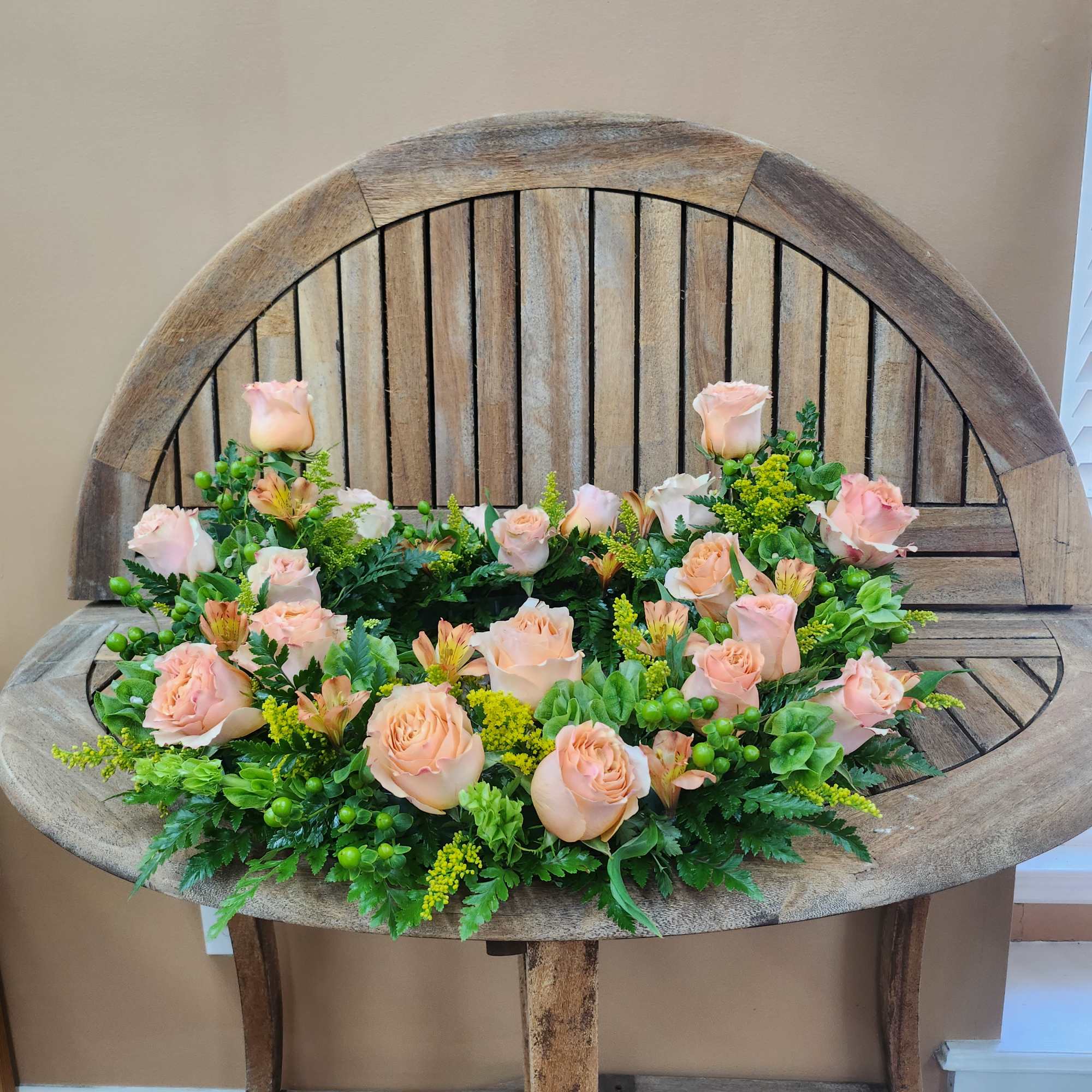 Low floral arrangement of pale peach roses on a wooden bench