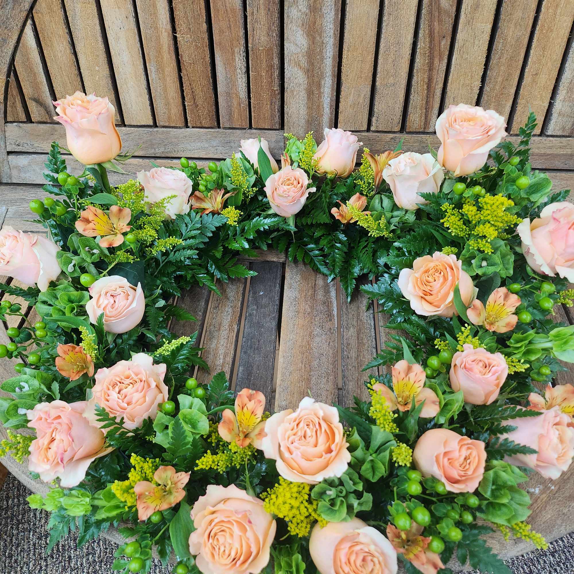 Peach rose floral wreath with green filler and small orange blooms