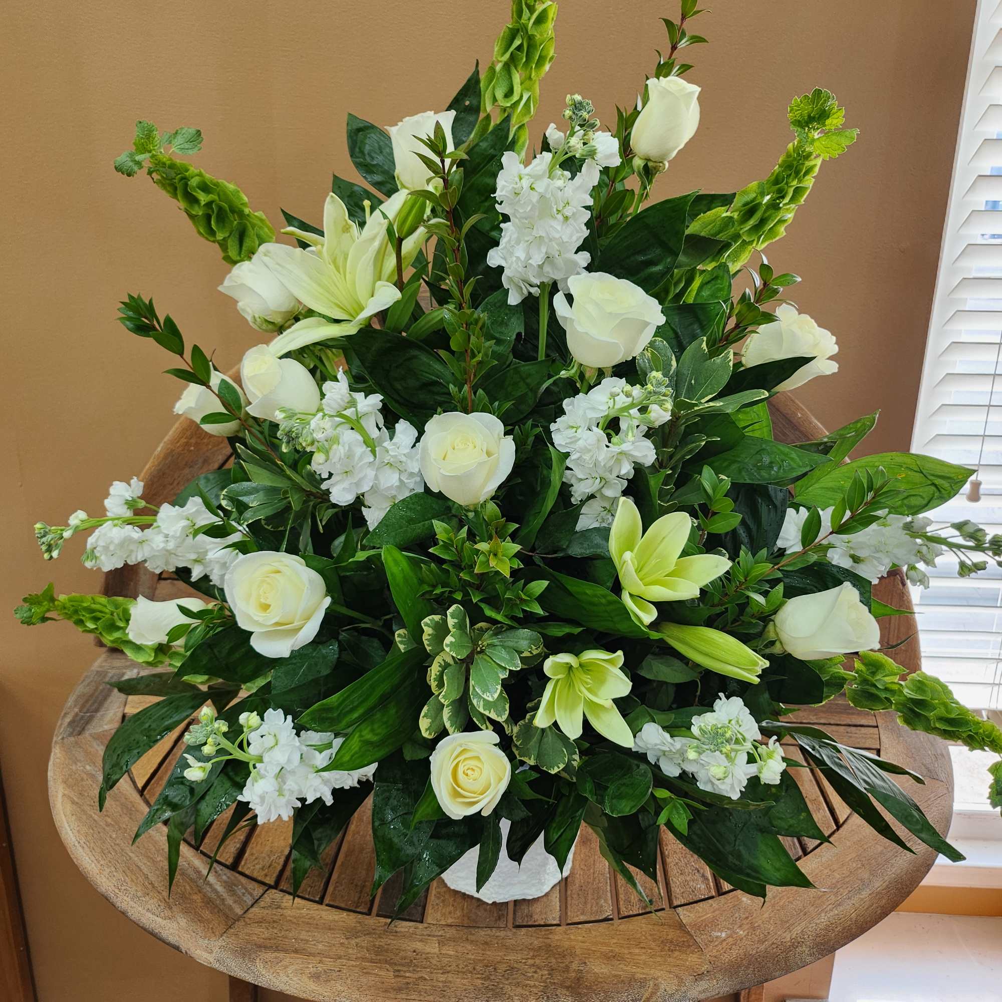 White roses and lilies arranged with green accents in a low centerpiece