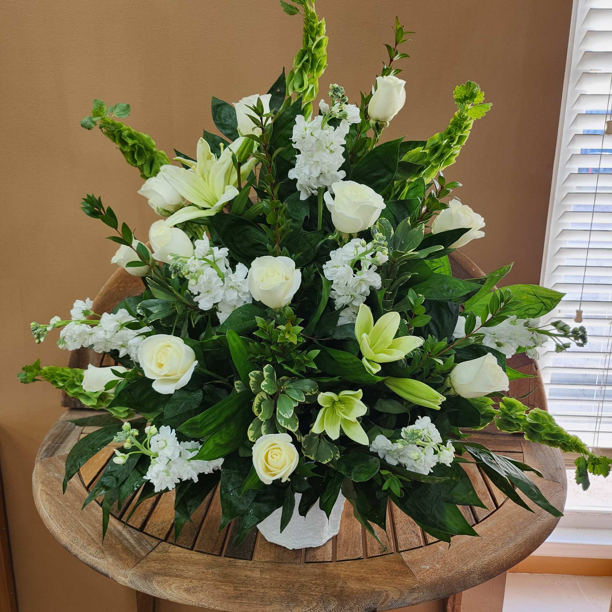 White floral arrangement with roses and lilies in a white vase