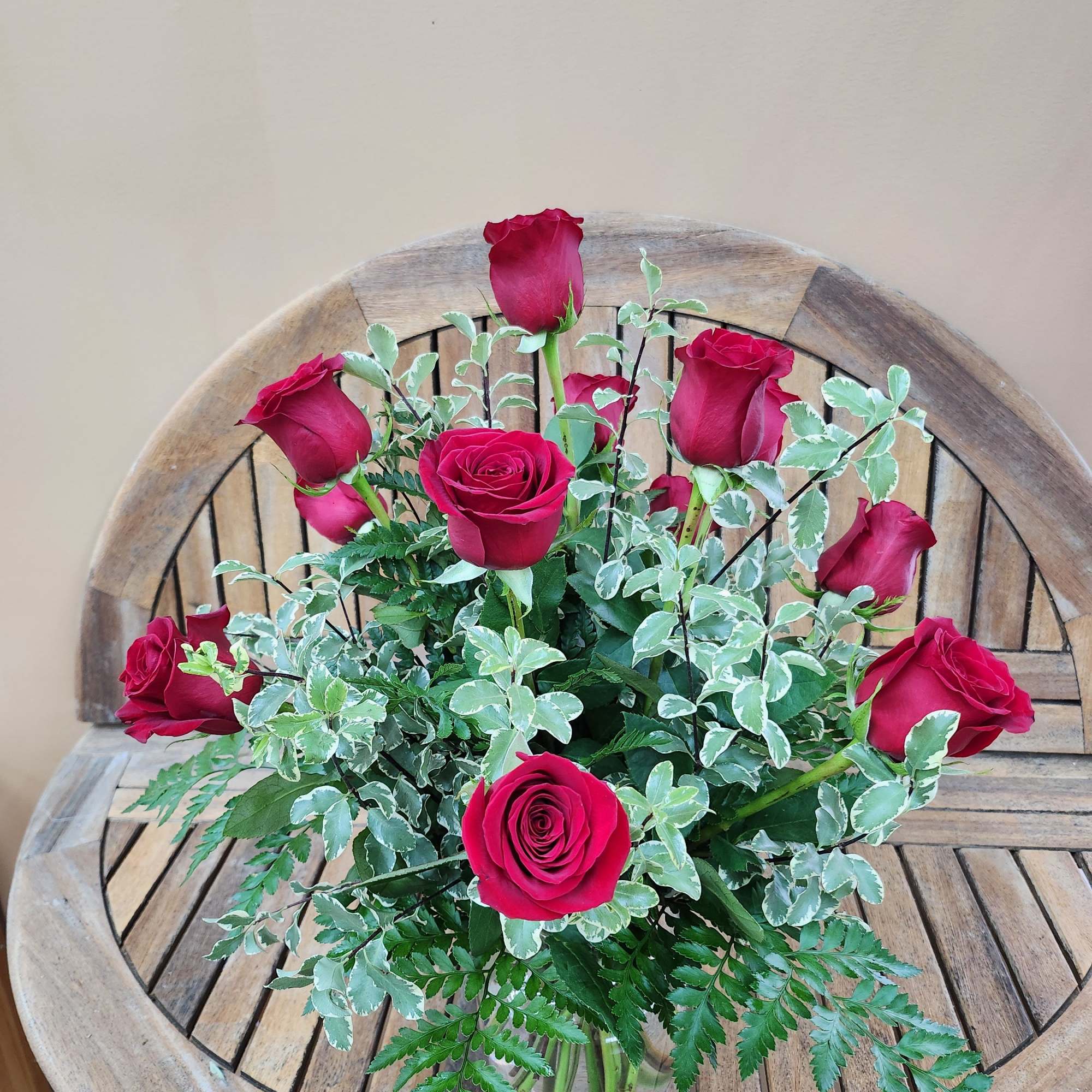 Bouquet of red roses with variegated greenery in a glass vase