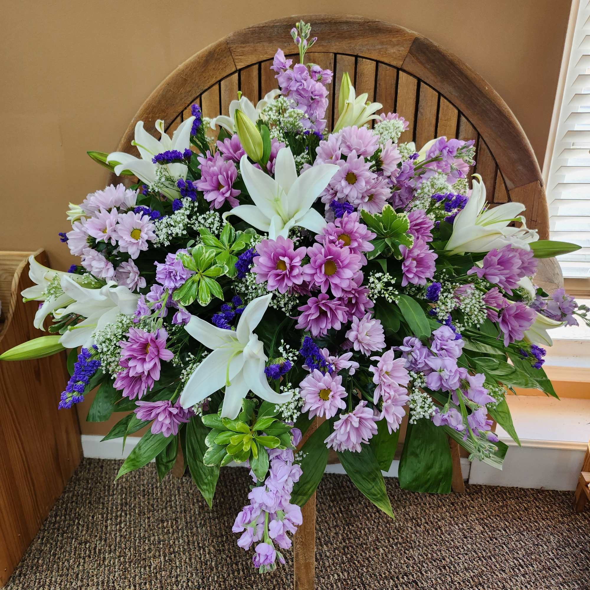 Lavender daisies and white lilies in a large standing spray