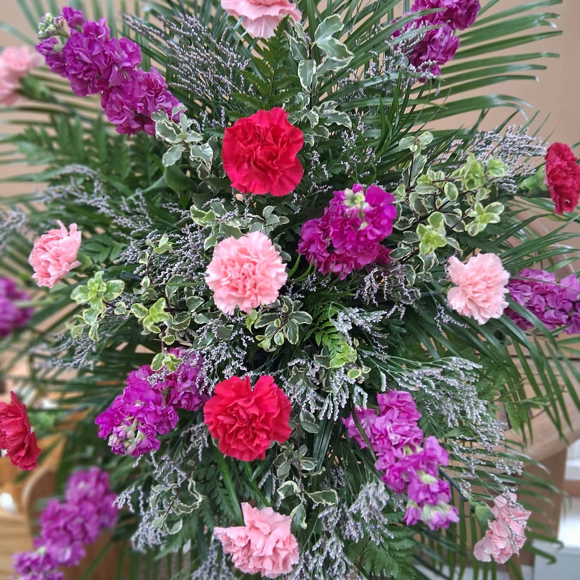 Standing floral spray with pink, purple, and red carnations