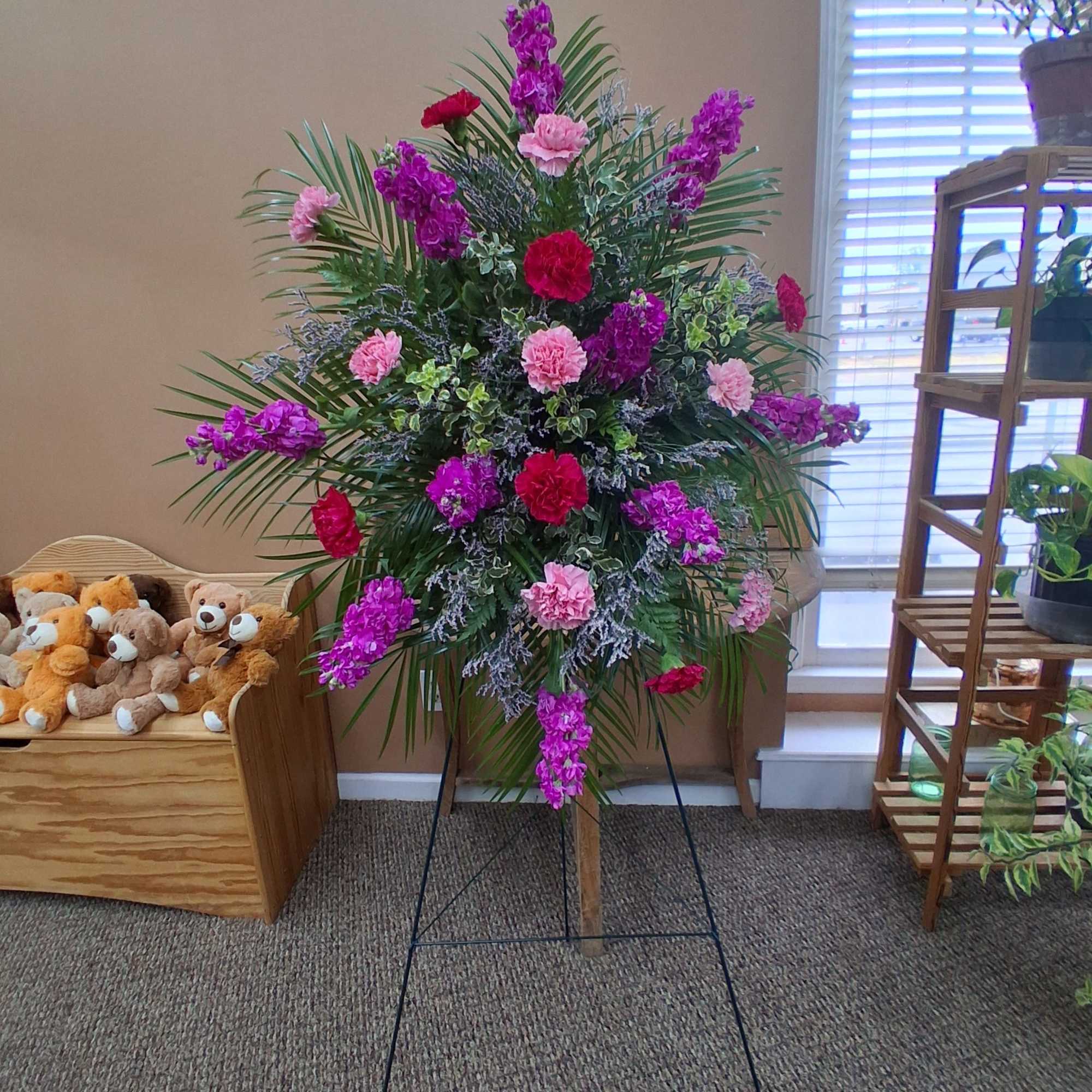 Standing floral spray with pink and purple blooms on a metal easel