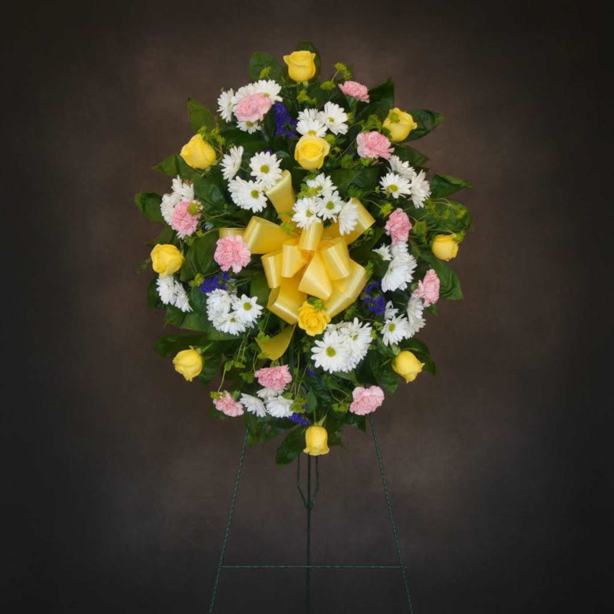 Standing floral wreath with yellow roses, white daisies, and pink carnations