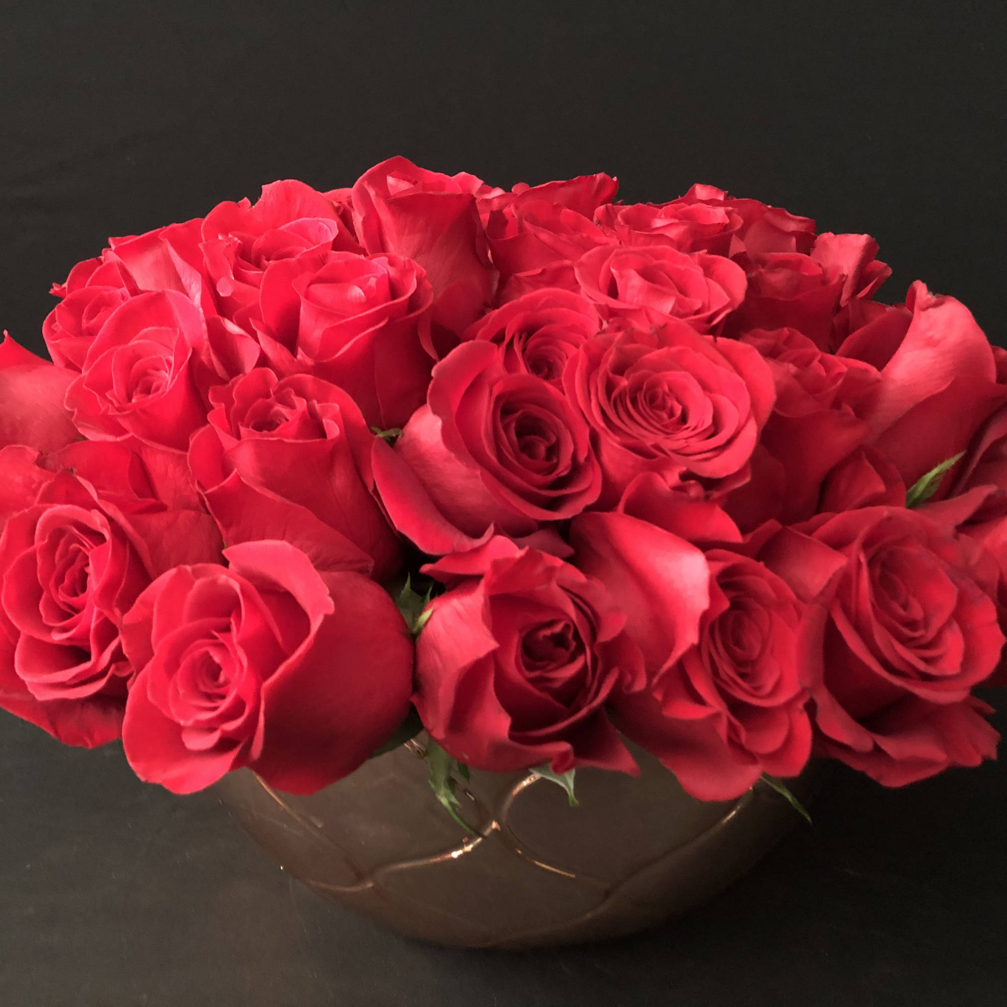Red rose bouquet in a low brown bowl vase