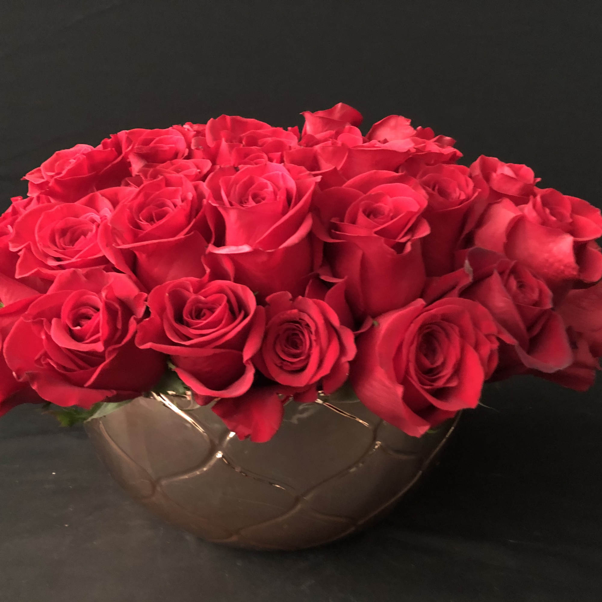Red roses arranged in a low round bowl vase