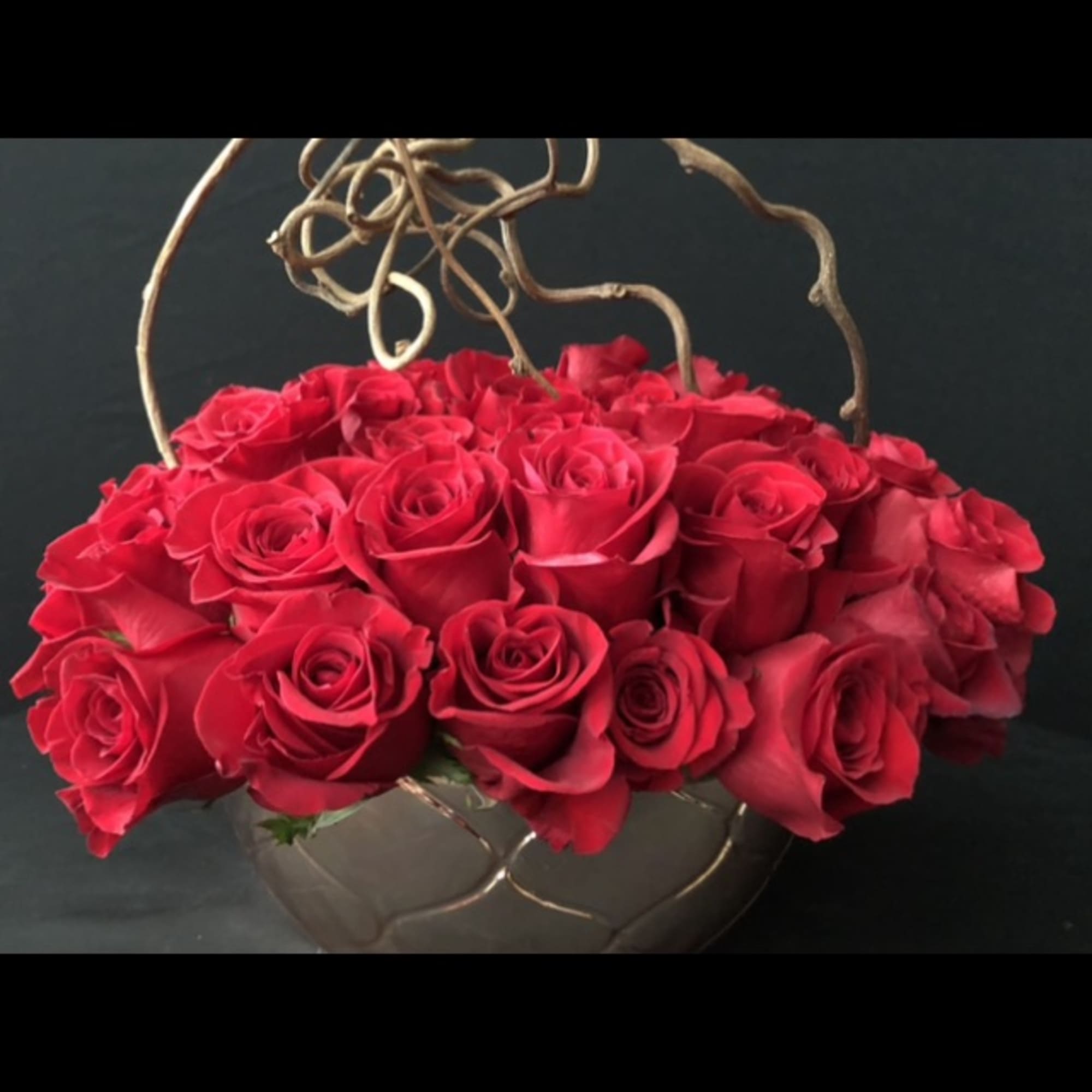 Basket of red roses with curly branches on a dark background