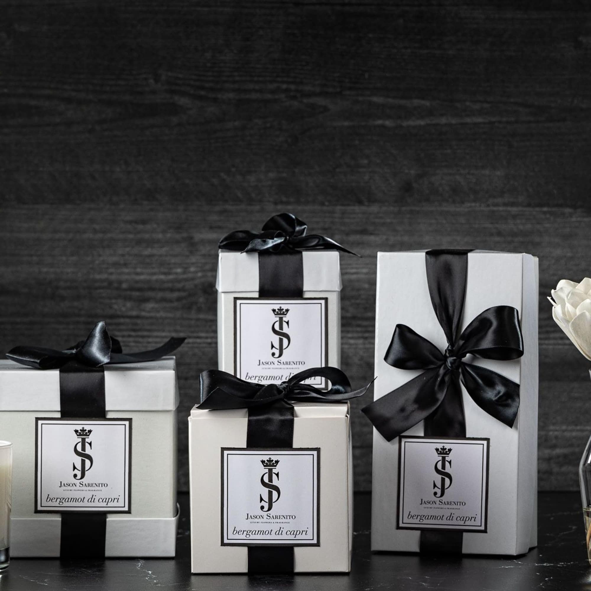 Gift boxes, a candle, and white flower stems in a glass vase