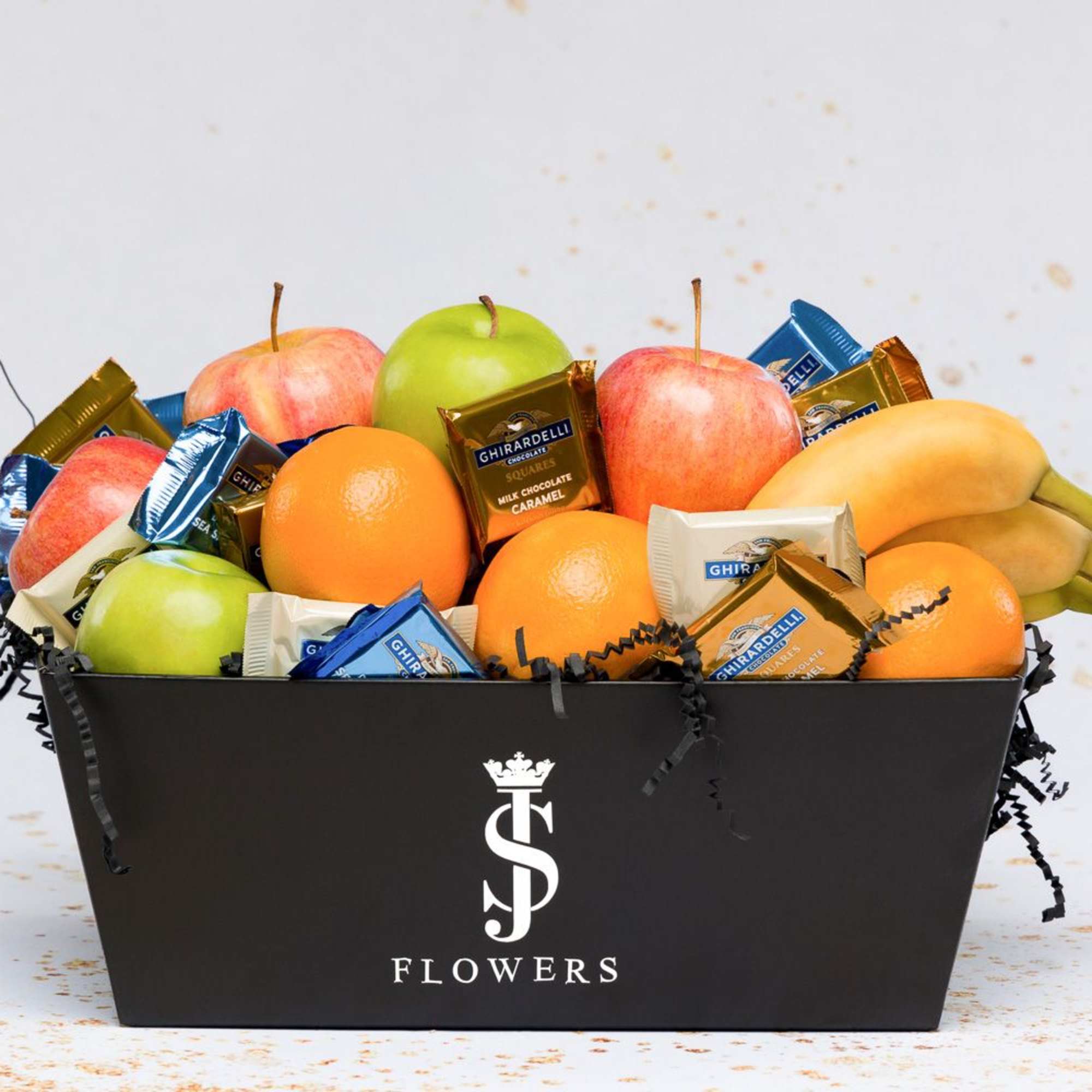 Fruit and chocolate gift box with apples, oranges, bananas, and wrapped candies