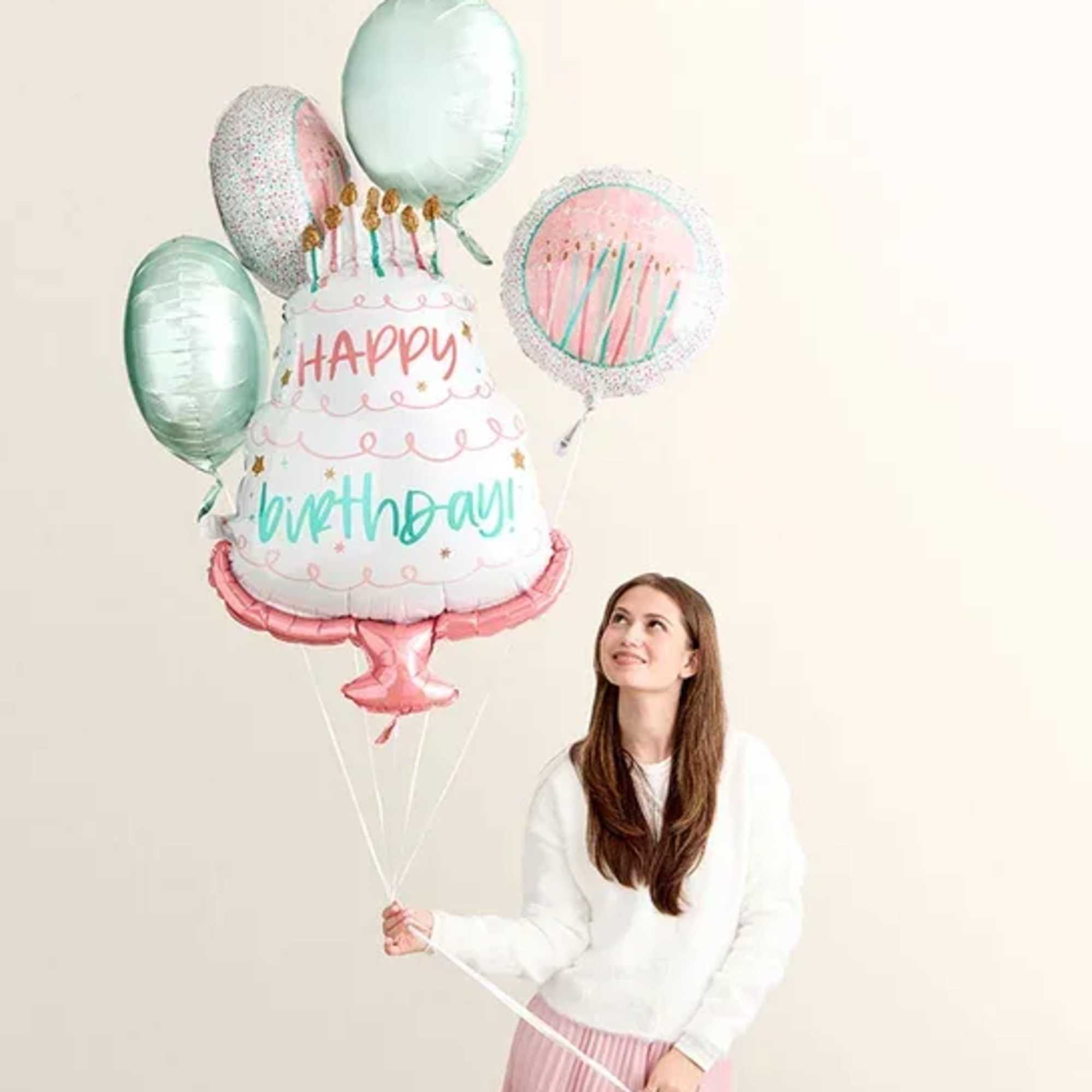 Woman holding birthday cake balloons with a "Happy Birthday" balloon