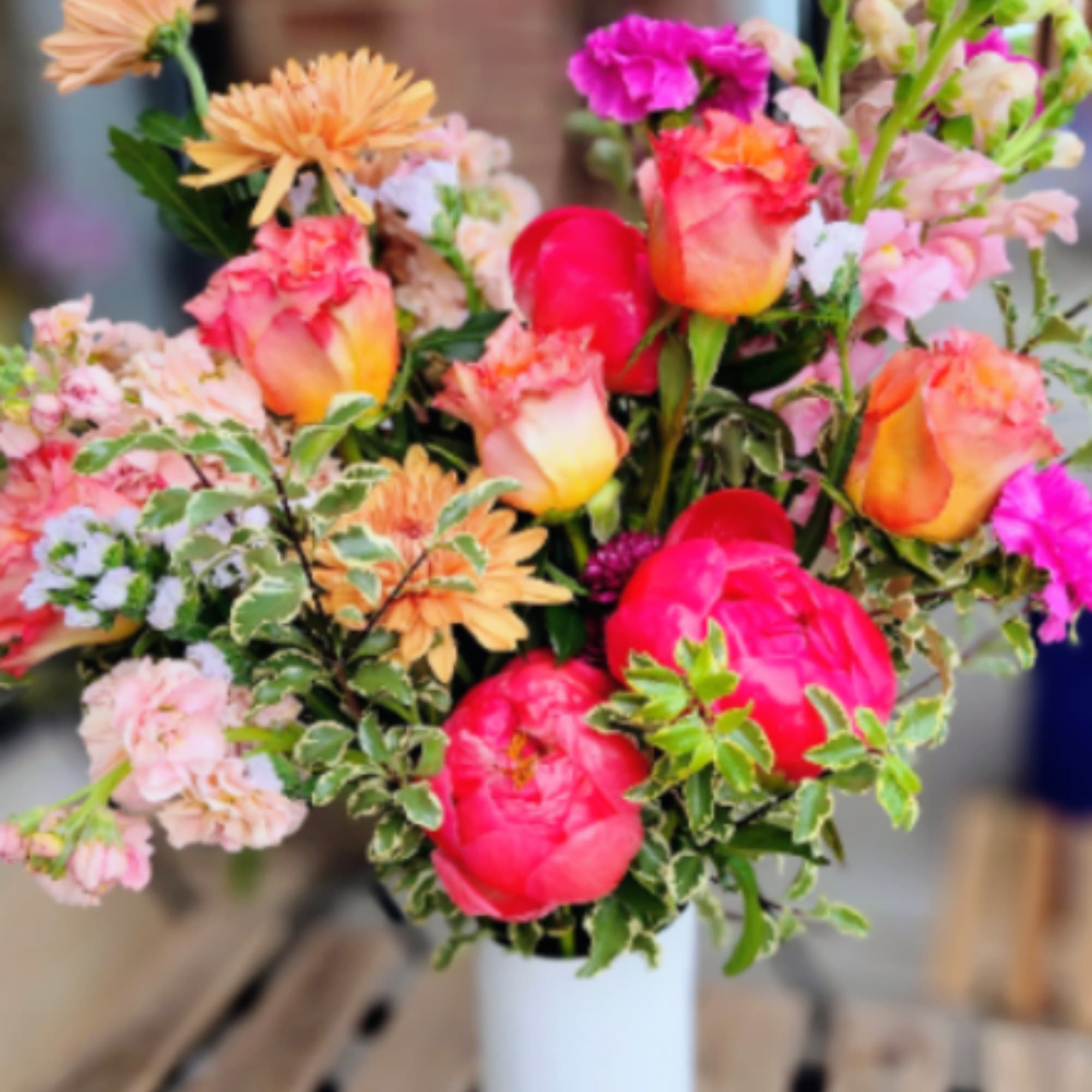 Mixed bouquet of pink and peach flowers in a white vase