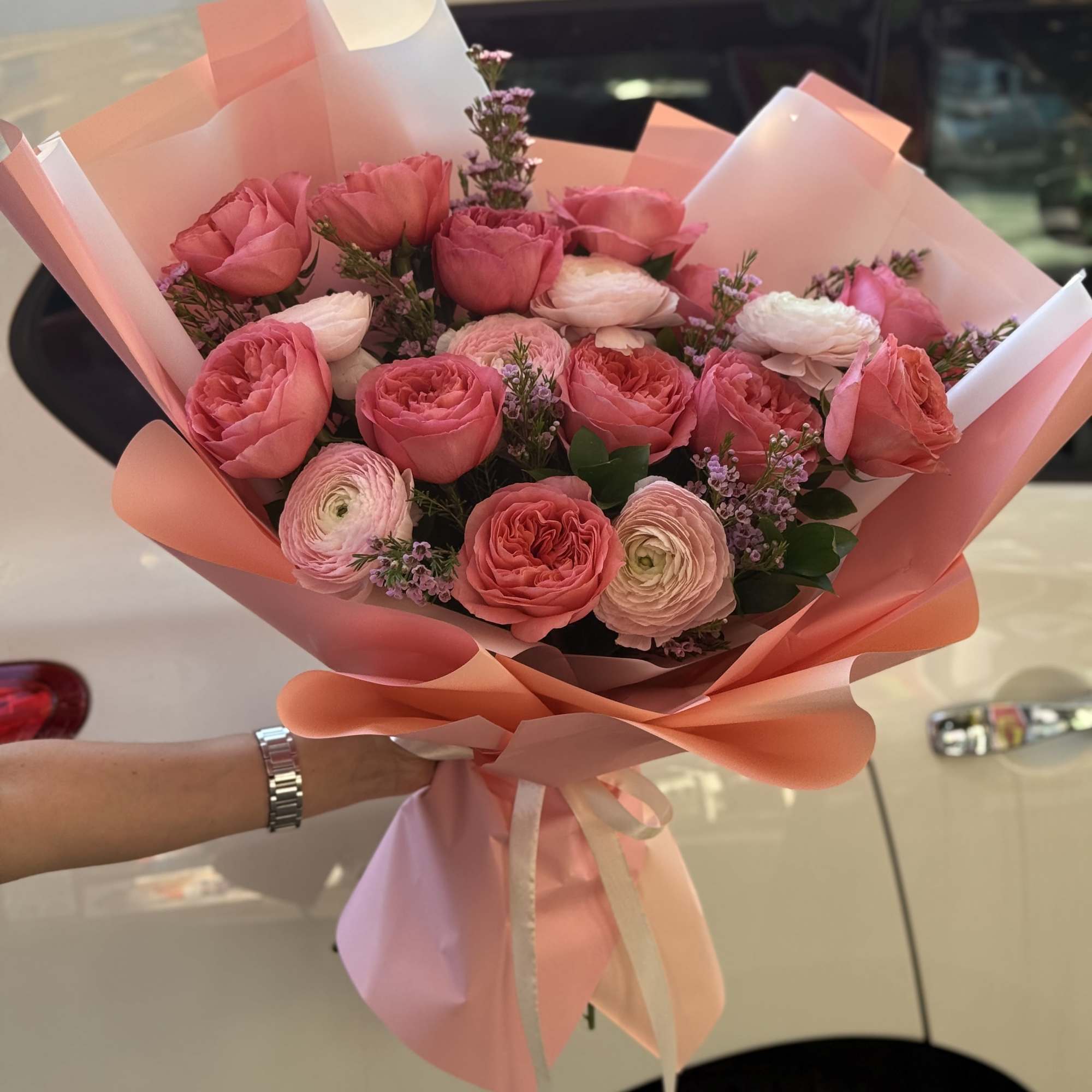 Pink rose and ranunculus bouquet wrapped in peach paper
