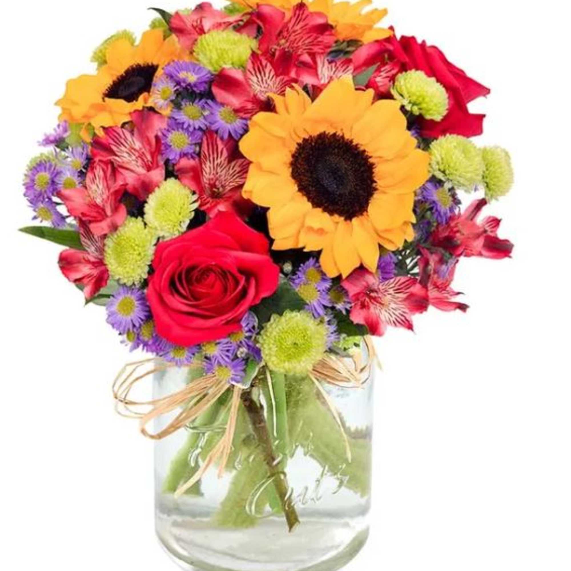Mixed bouquet of sunflowers, roses, and small purple flowers in a glass vase