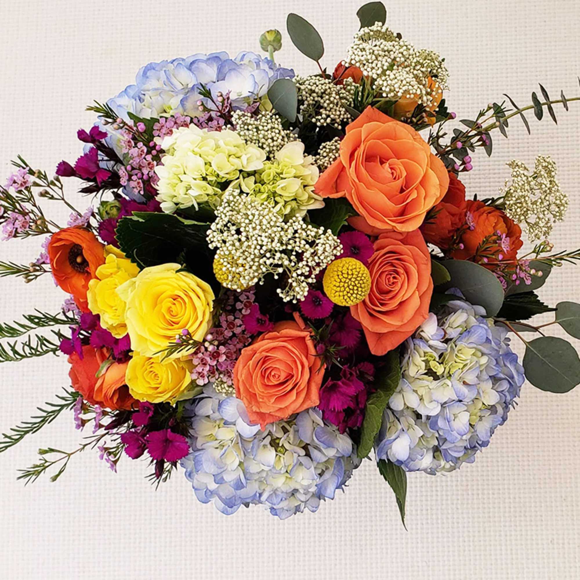 A vibrant mix of yellow and orange roses beautifully contrasted with blue, photo 2 of 2