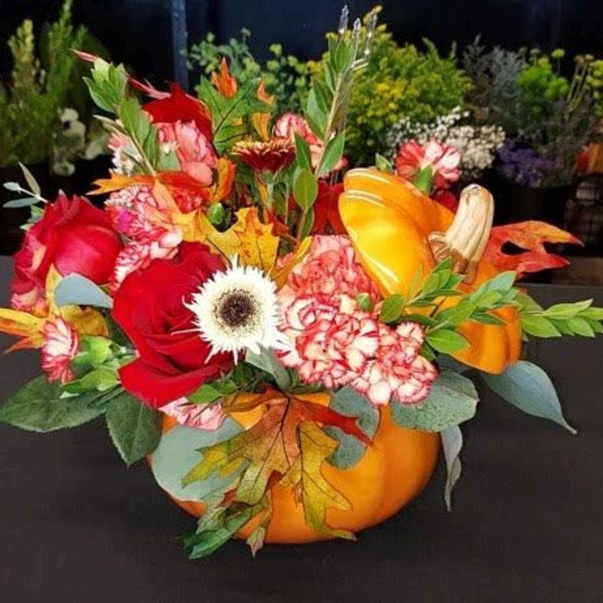 Pumpkin-shaped floral arrangement with red and orange blooms