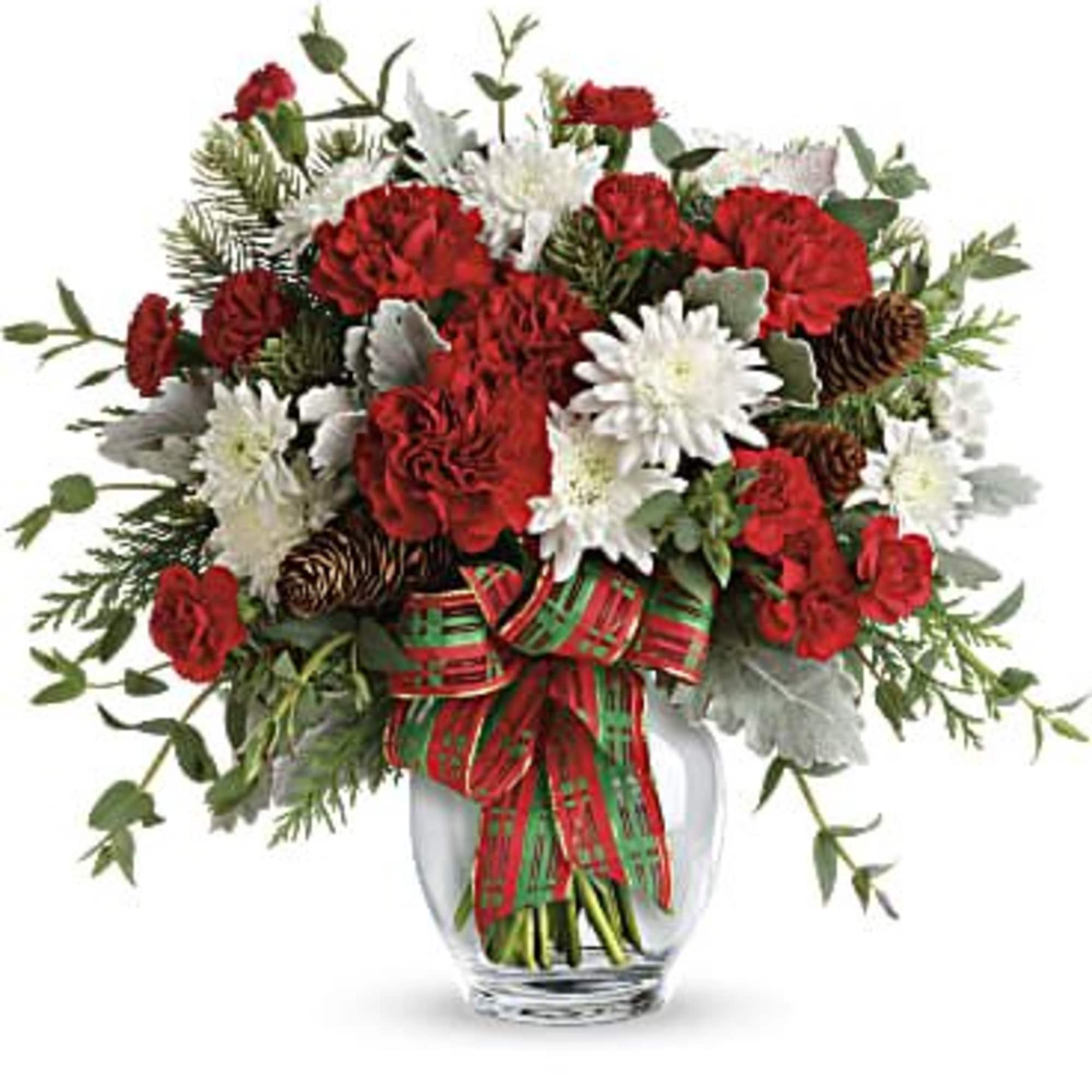 Red and white flowers arranged in a clear glass vase with a plaid ribbon