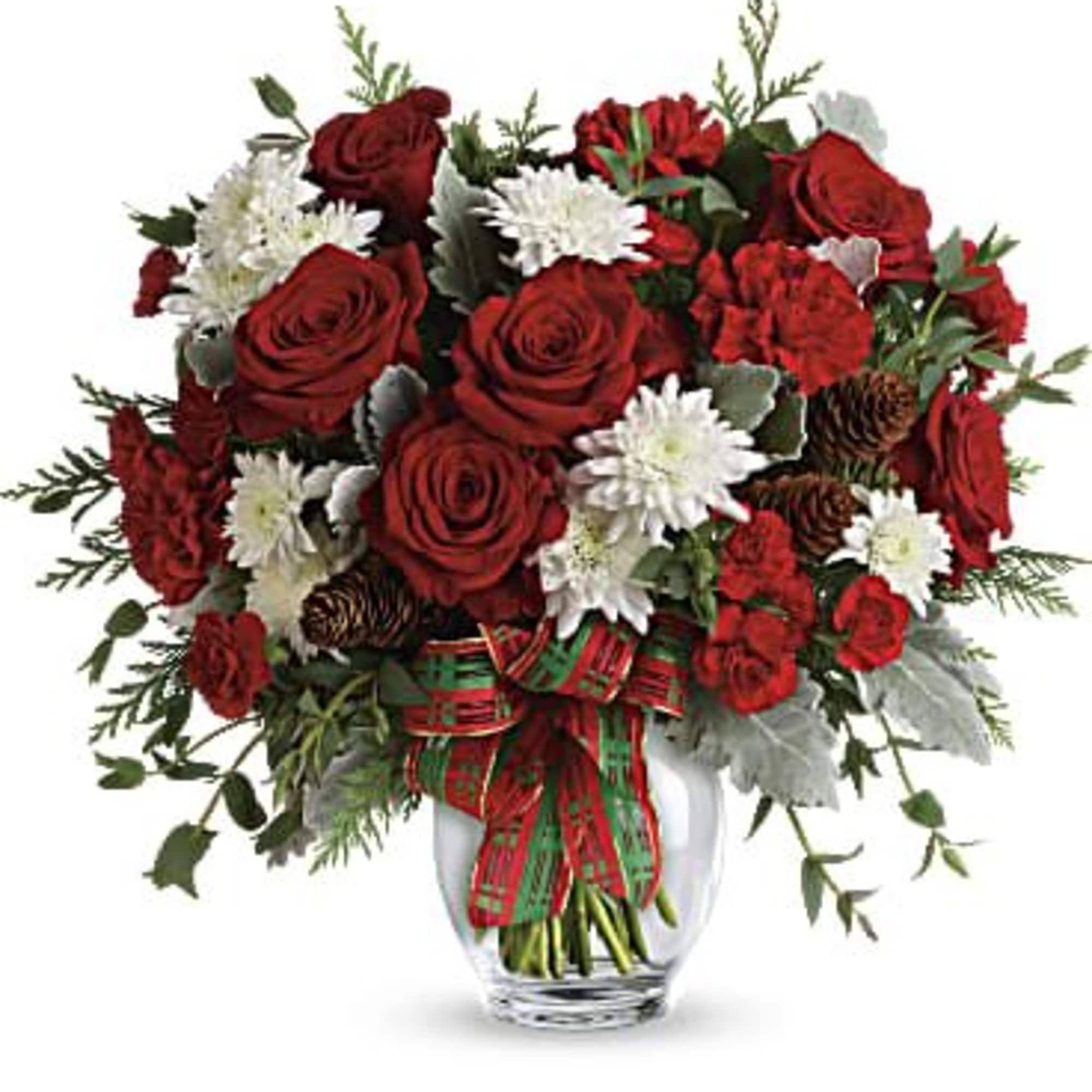 Red roses and white flowers arranged in a clear glass vase with a plaid ribbon
