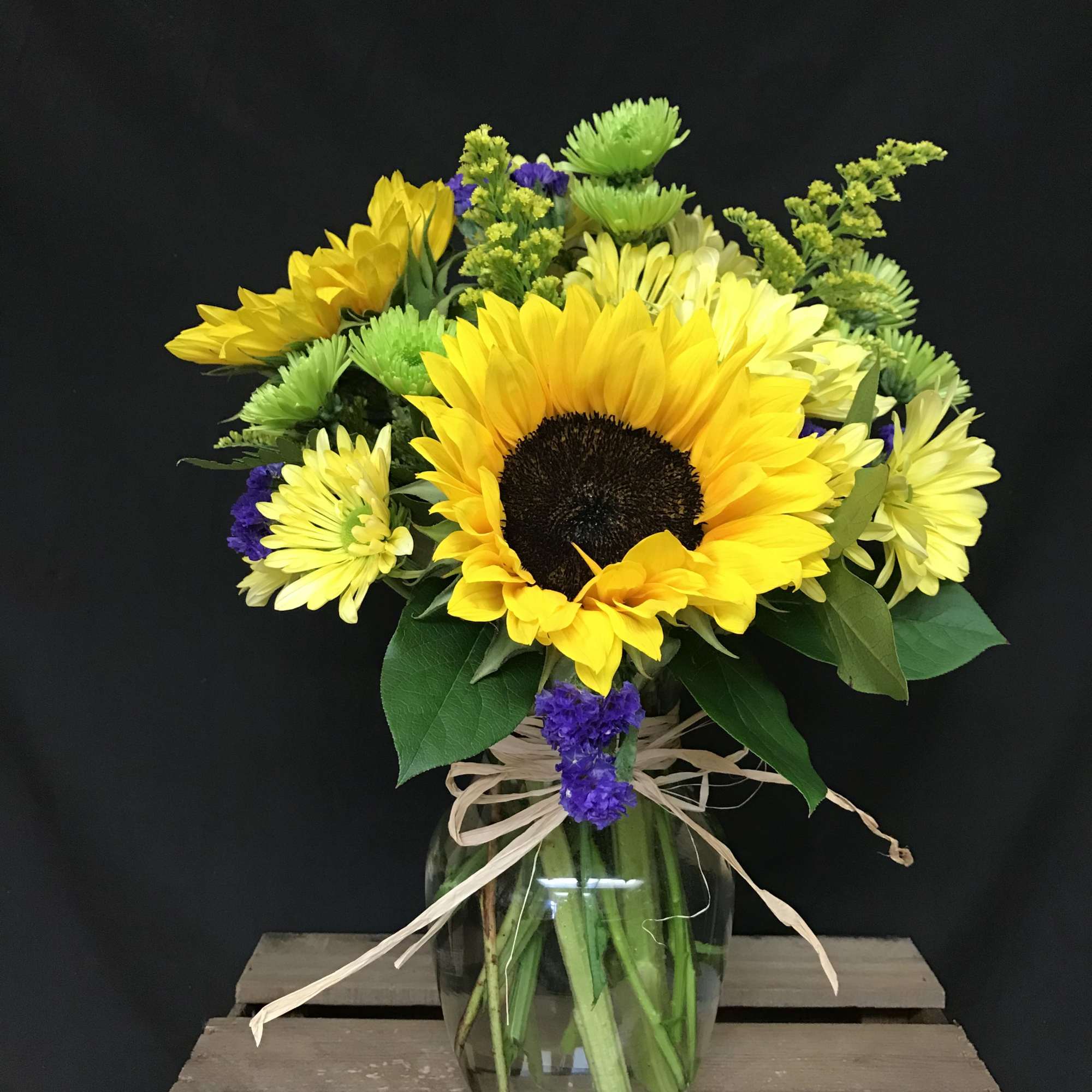Sunflower bouquet in a glass vase with yellow and purple flowers
