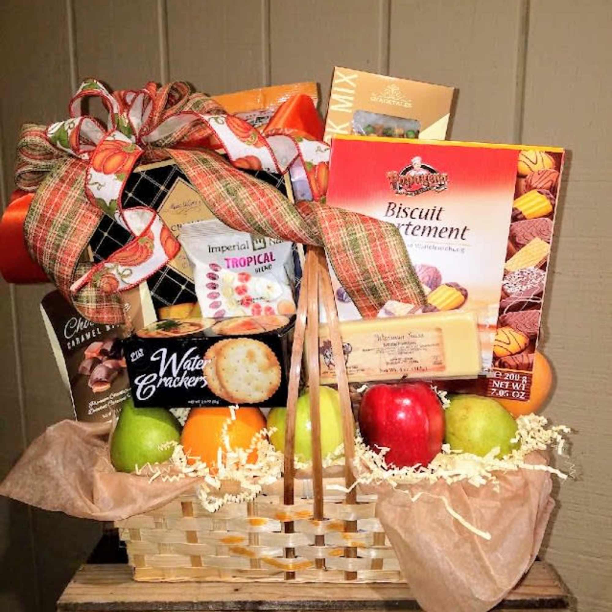 Gift basket with fruit and assorted snack boxes tied with a large ribbon