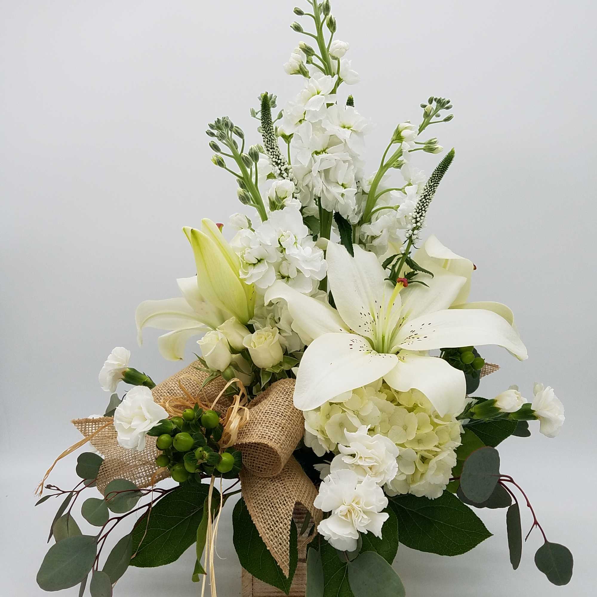 White lilies and hydrangeas in a rustic box arrangement