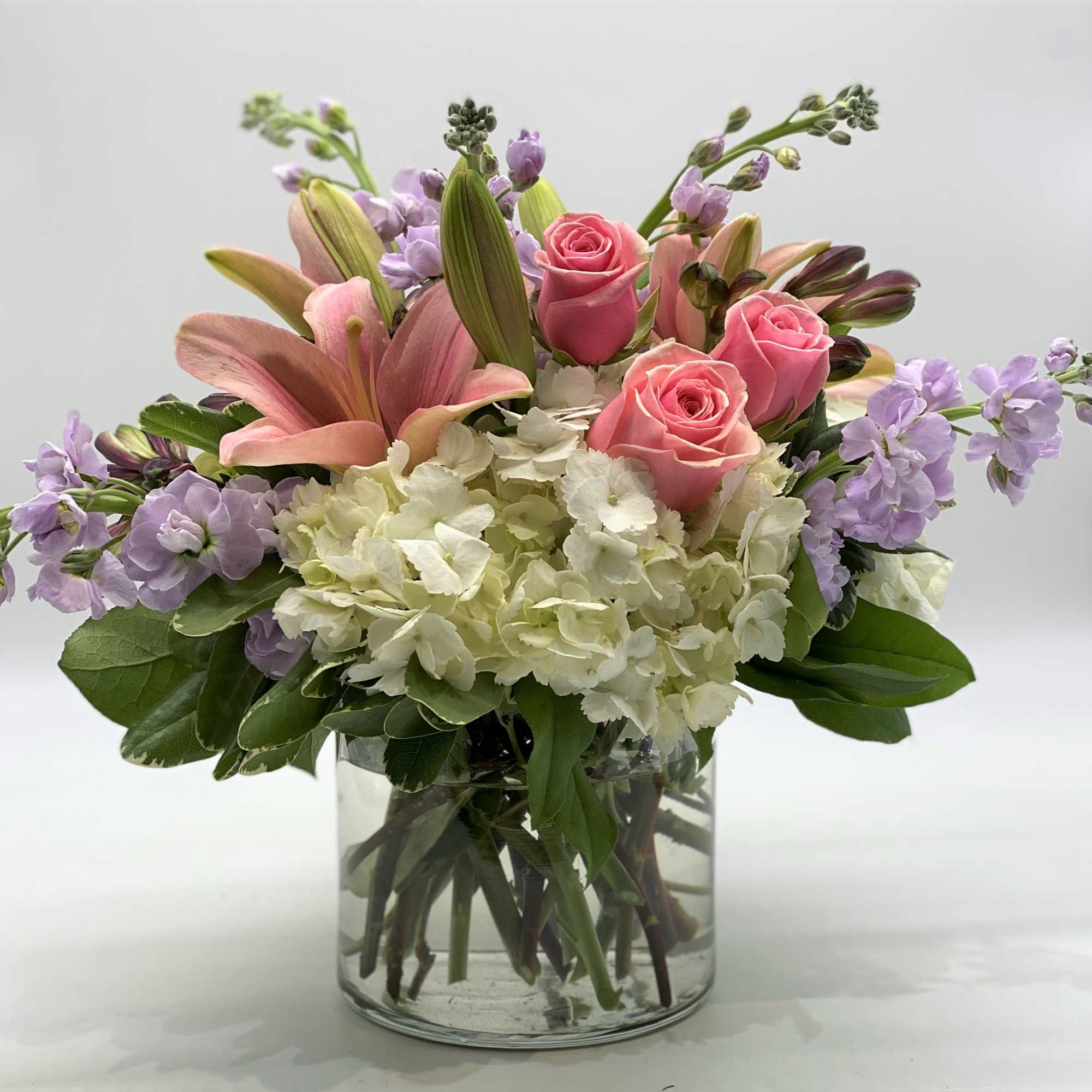 Pink roses and lilies with white hydrangeas in a glass vase
