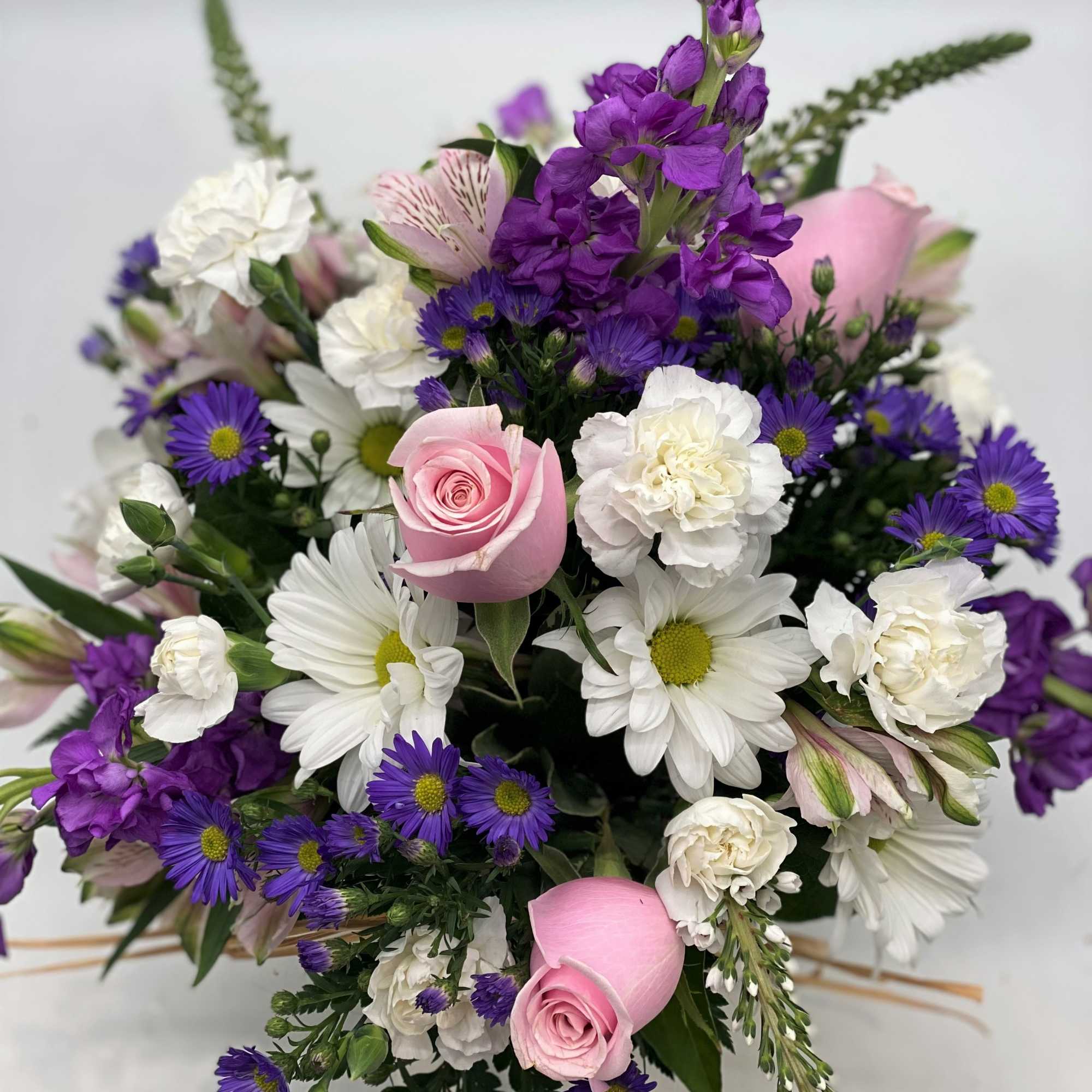 Bouquet of pink roses, white daisies, and purple flowers