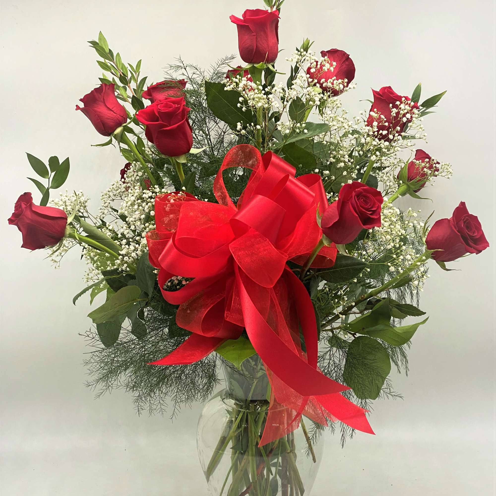 Red roses in a clear glass vase with a large red bow, photo 2 of 4